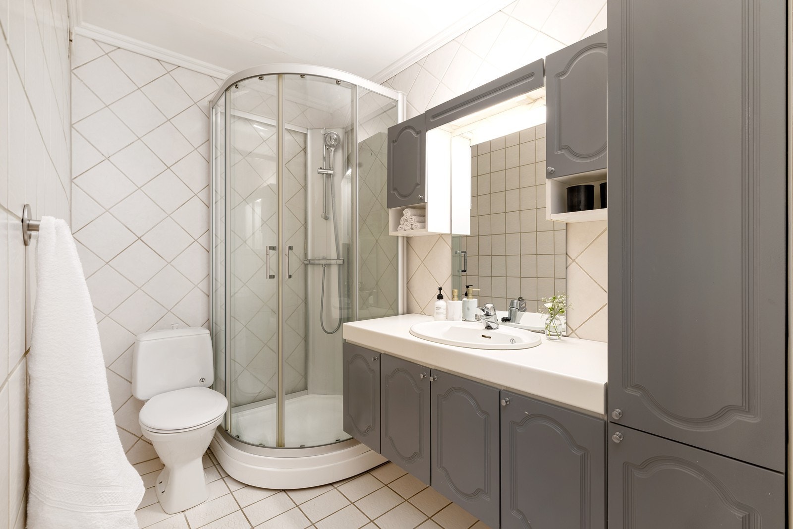 Videre er det er flislagt baderom med varme i gulv. Badet har dusjkabinett, servant med innredning og toalett. Galleribilde