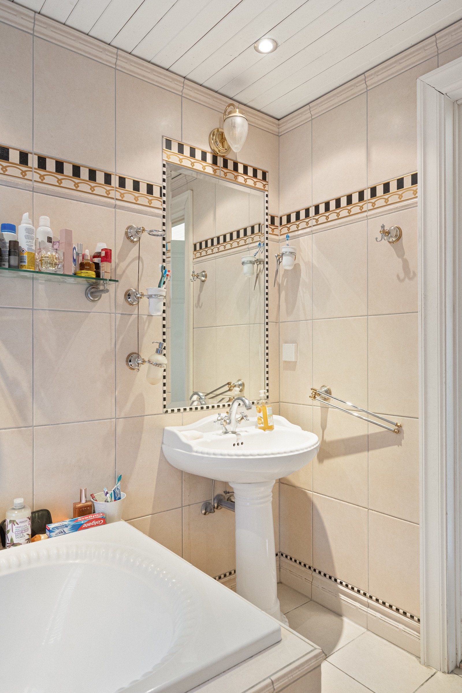 Badet er innredet med fasiliteter som et innfliset badekar, et separat dusjhjørne med glassvegg og en elegant håndkletørker. Galleribilde