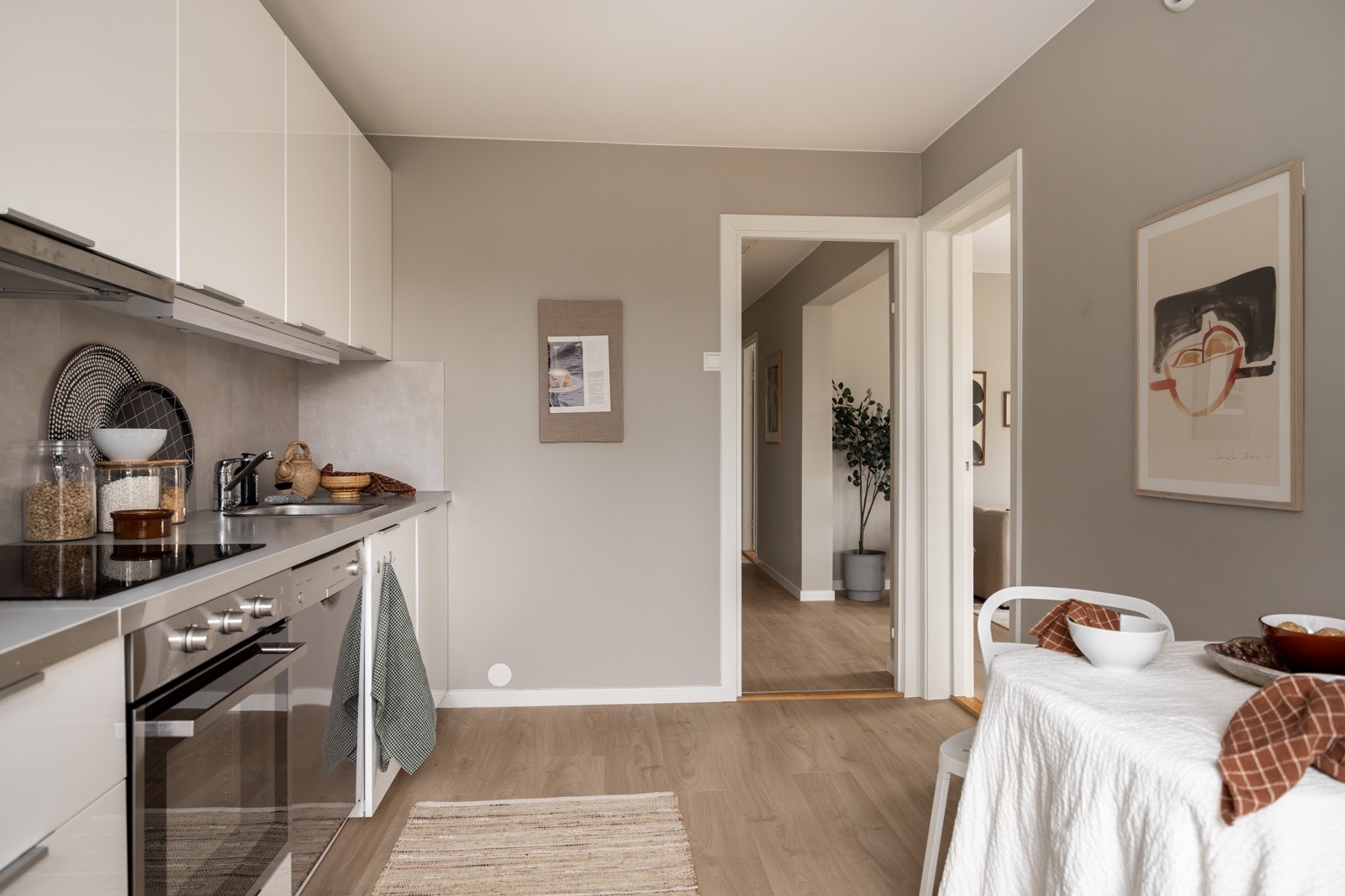 Moderne og tidløs kjøkkeninnredning fra Ikea med god skap- og benkeplass. Innredningen har hvite glatte fronter og laminert benkeplate med nedfelt oppvaskkum. Både stilrent og praktisk med plater i benkeryggen og belysning under overskapene. Galleribilde