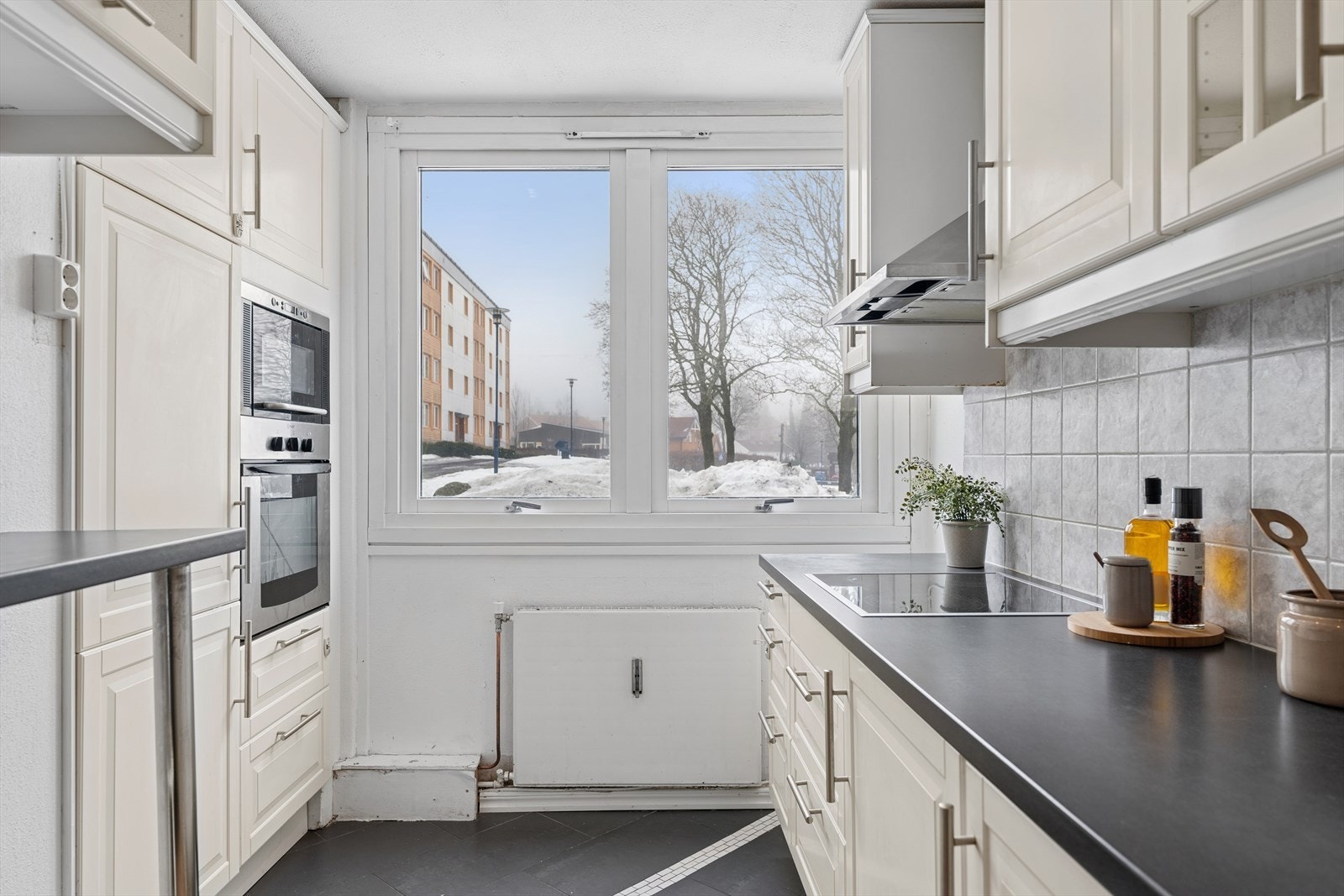 Kjøkken med innredning bestående av profilerte fronter og benkeplate i laminat, med dobbel stålkum. Integrerte hvitevare medfølger ved salg. Galleribilde