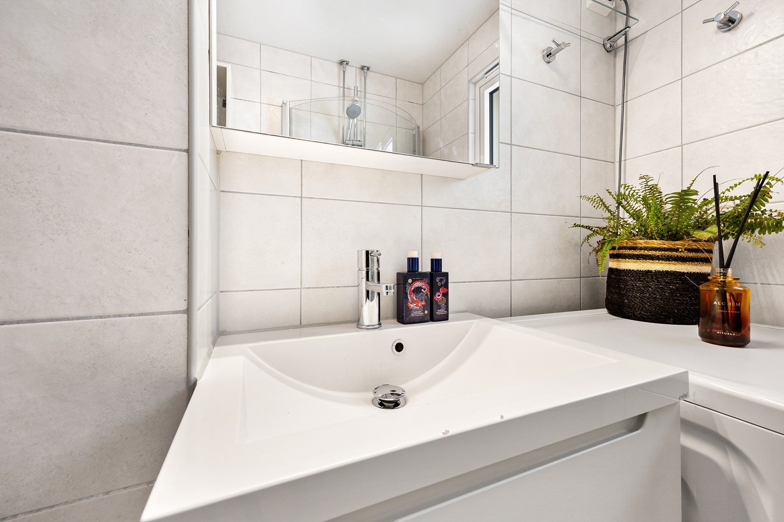 Badet består av servantseksjon med skuffer og overskap med speilfronter, dusjhjørne, vegghengt toalett og opplegg for vaskemaskin Galleribilde