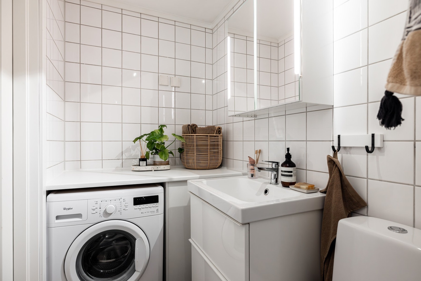 Flislagt baderom med varme i gulv og praktisk nisje for vaskemaskin. Galleribilde