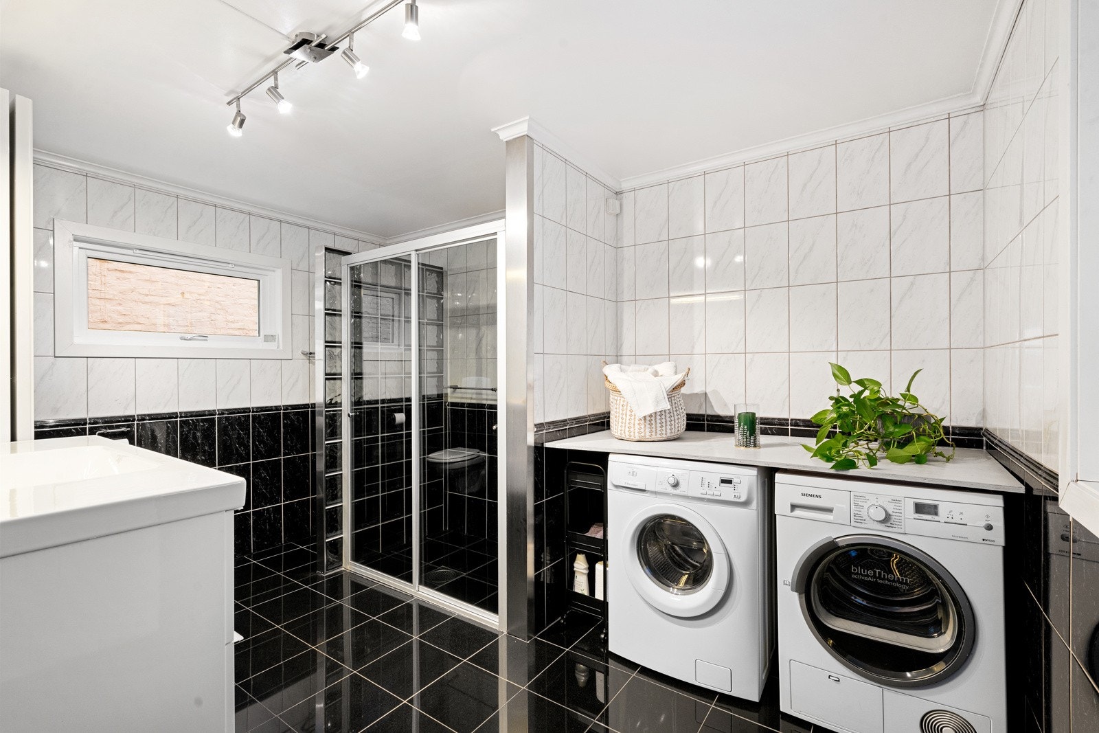 Flislagt bad med vegghengt toalett, dusj, servant med innredning og opplegg for vaskemaskin/tørketrommel Galleribilde