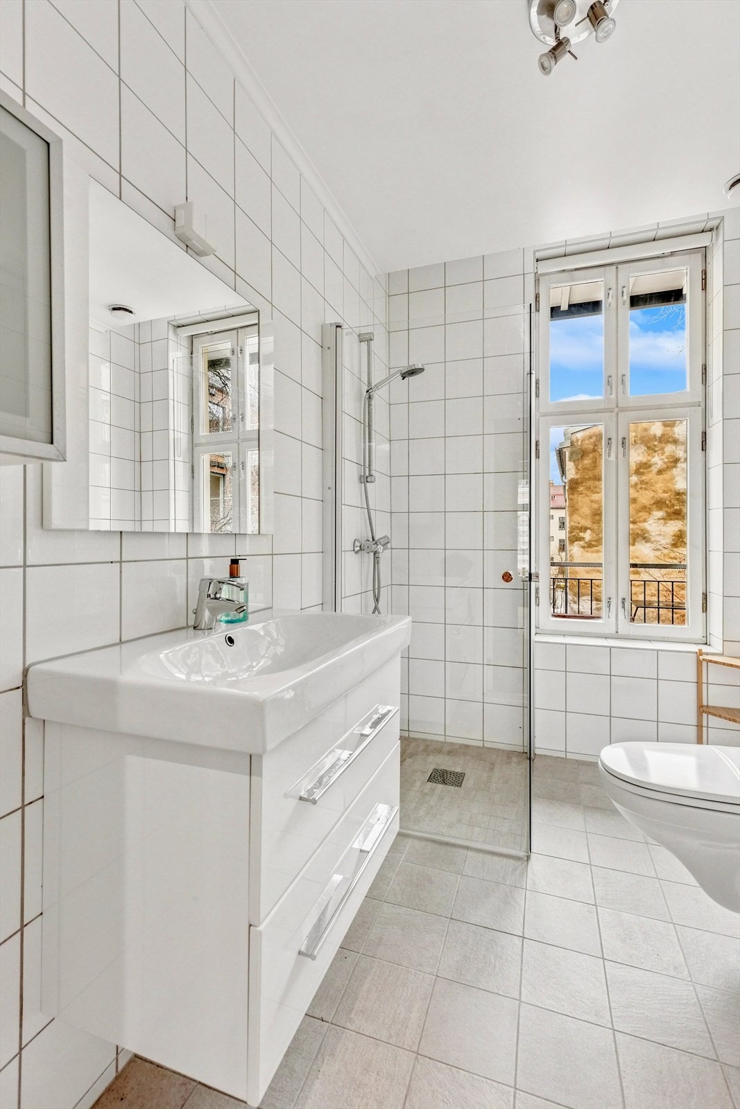 Badet består av vegghengt wc, speil, veggskap og inn-/utadslående dusjdører Galleribilde