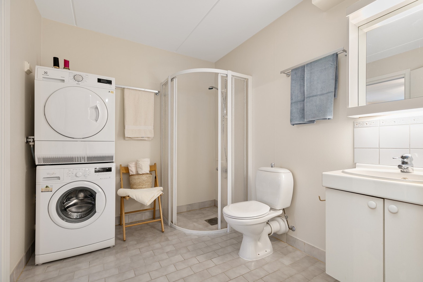 Leilighetens bad fra 1995 er innredet med vaskemaskin, dusjhjørne, toalett og servant med underskap og speil. Galleribilde