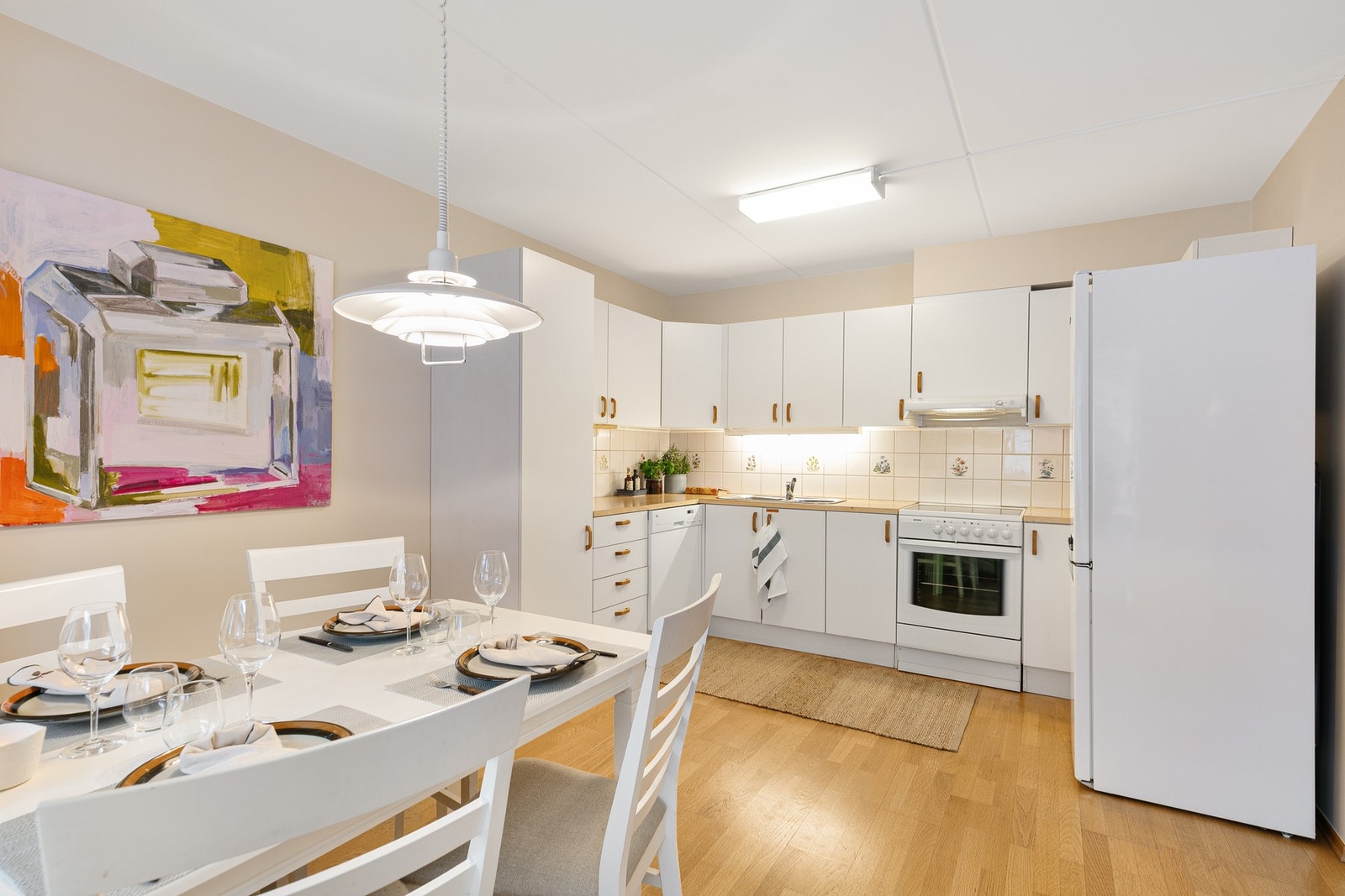 Kjøkkenet har innredning fra byggeår med glatte hvite fronter og benkeplater i laminat. Galleribilde