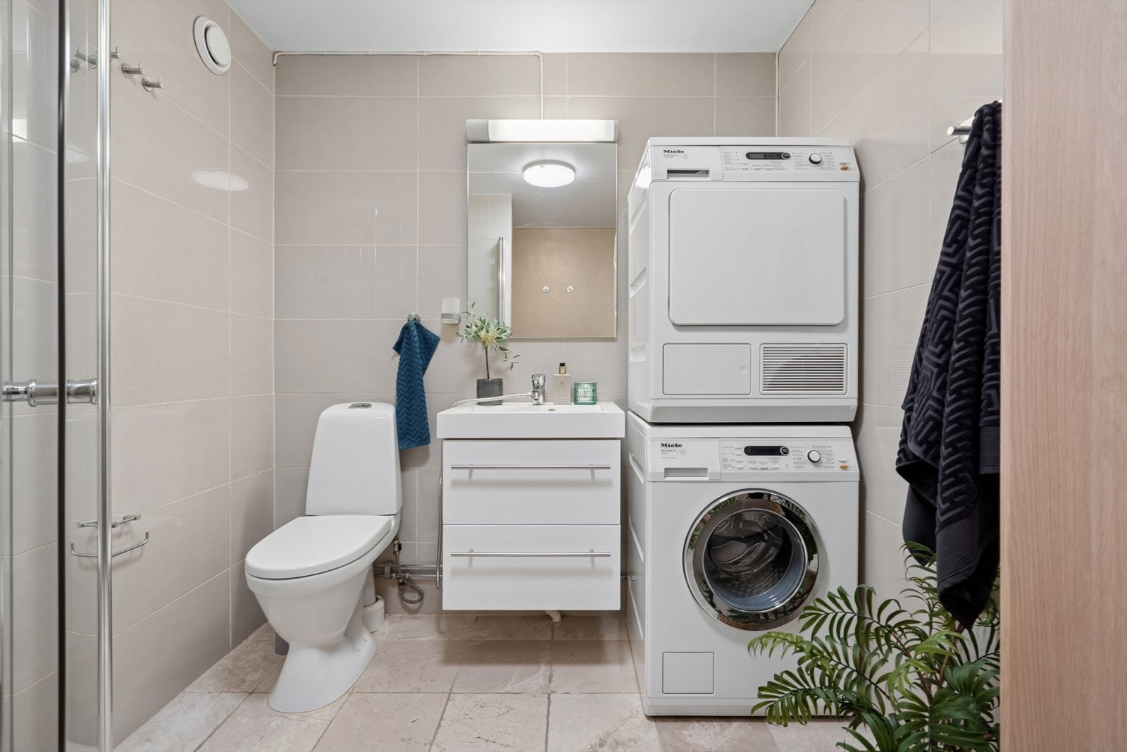 Flislagt baderom med varmekabler i gulvet, opplegg for vaskemaskin og plass til tørketrommel. Galleribilde