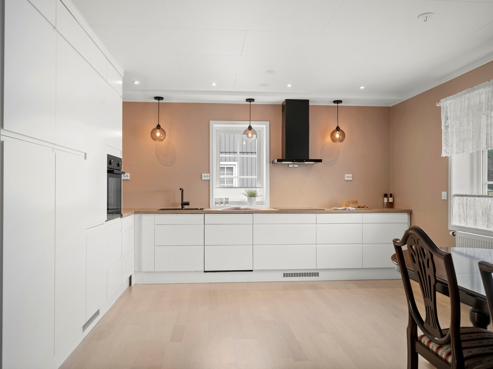 EPOQ kjøkken fra 2023 og har god oppbevaringsplass i en innredning med hvite, slette fronter. Det er også gode arbeidsflater på en benkeplate av laminat. Galleribilde