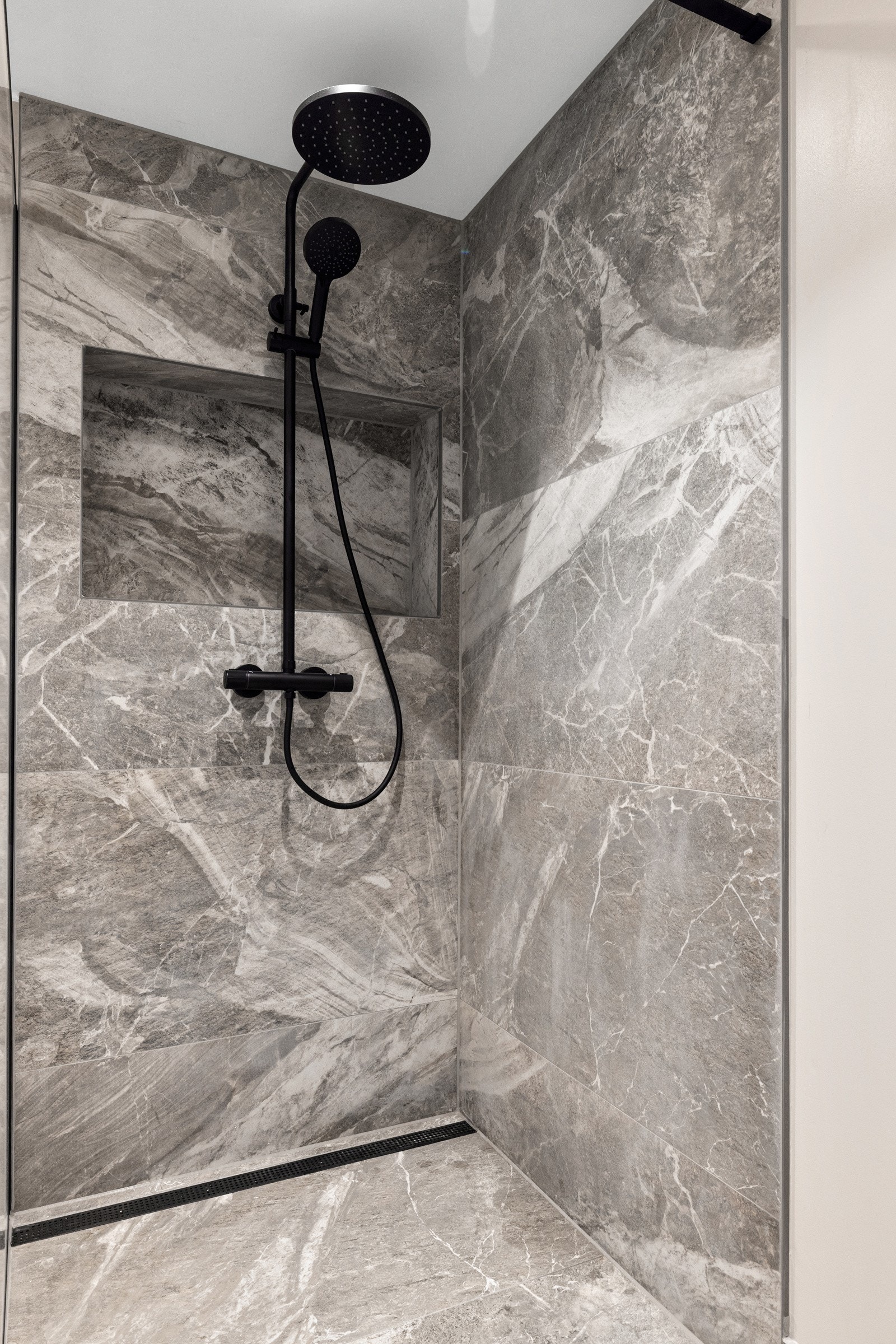 Dusjhjørne med regnfall- og hånddusj. Plassbygget nisje for oppbevaring. Galleribilde