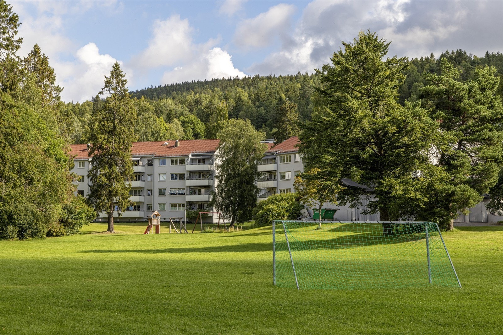 Fellesområdet foran blokken har flere pent opparbeidete grøntarealer, sittegrupper, lekeplasser og bålpanne. Galleribilde