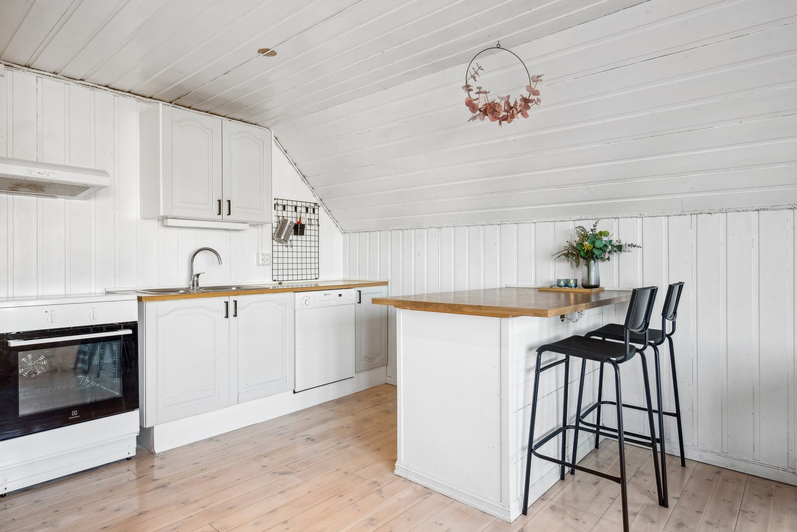Lyst kjøkken med komfyr, oppvaskmaskin og kjøleskap. Galleribilde