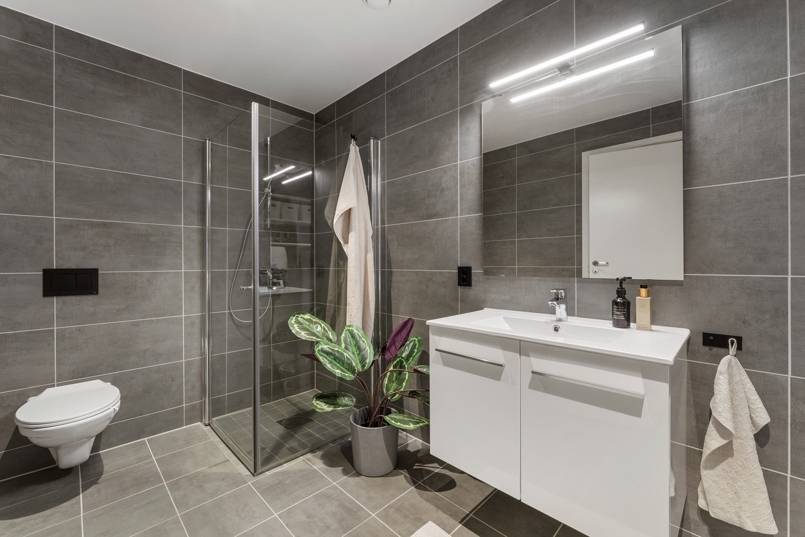 Baderommet er utstyrt med dusjhjørne, vegghengt toalett, opplegg for vaskemaskin/tørketrommel og baderomsinnredning med heldekkende servant, samt belyst speil Galleribilde