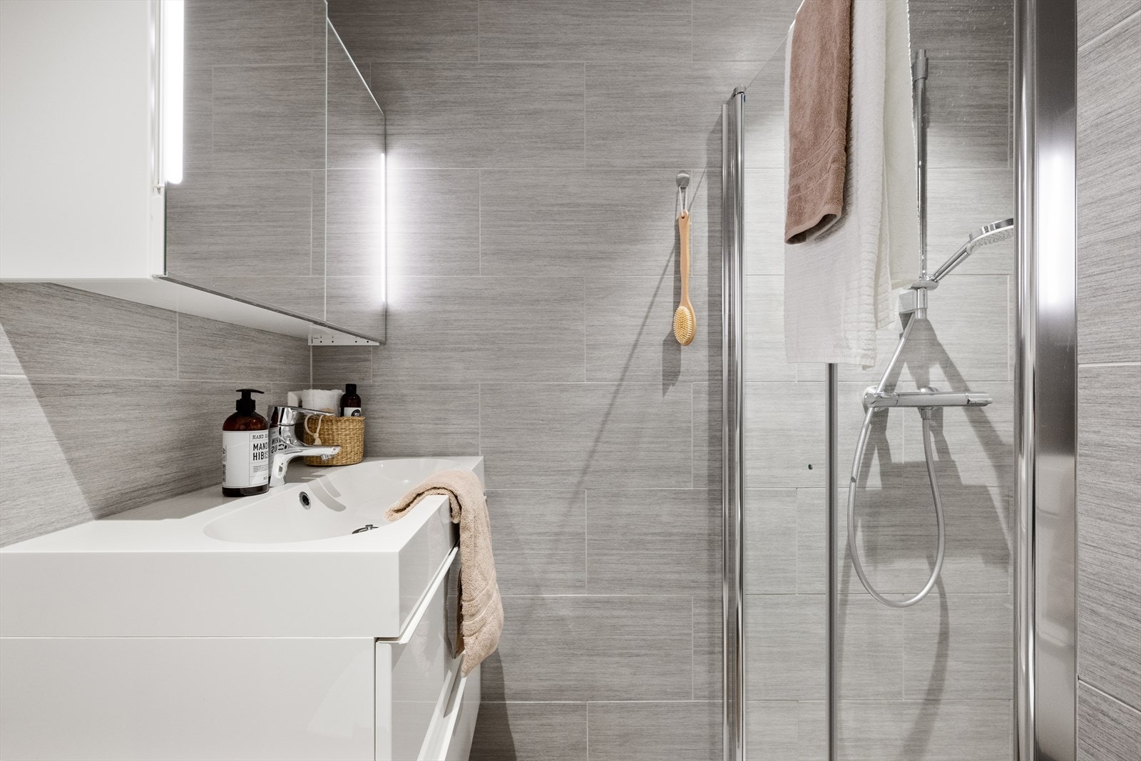 Badet er innredet med nedfelt servant i baderomsmøbel, toalett og dusjhørne. Galleribilde