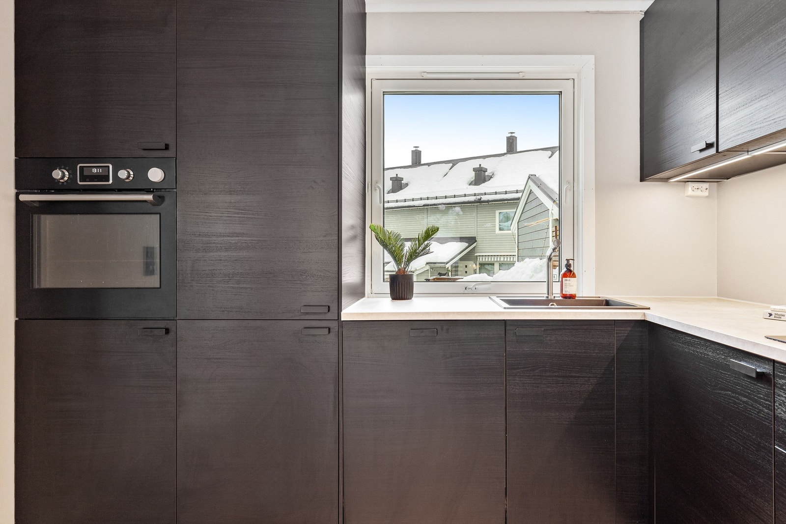 Kjøkkeninnredningen er stilfull og tidløs med glatte fronter og laminat benkeplate med nedfelt vaskekum. Av integrerte hvitevarer er det induksjonstopp, stekeovn, oppvaskmaskin og kombinert kjøleskap med frys. Galleribilde