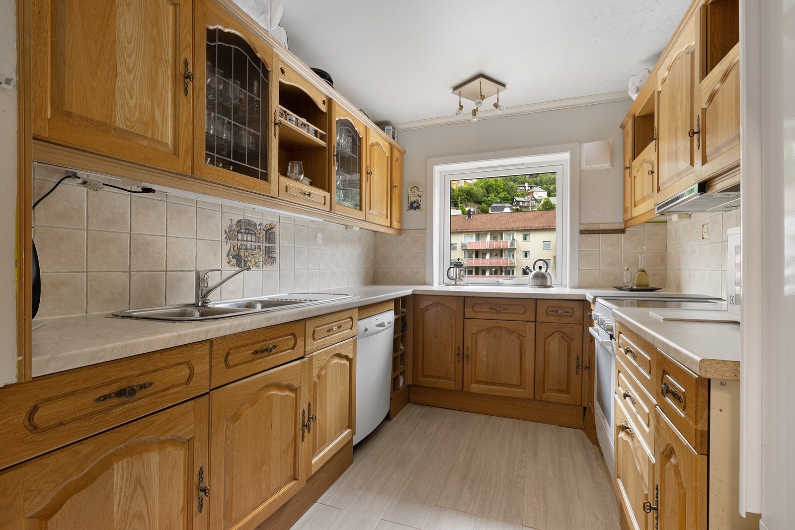 Stort kjøkken i heltre som er innredet med profilerte fronter i eik, laminert benkeplate og kjøkkenfliser. Galleribilde