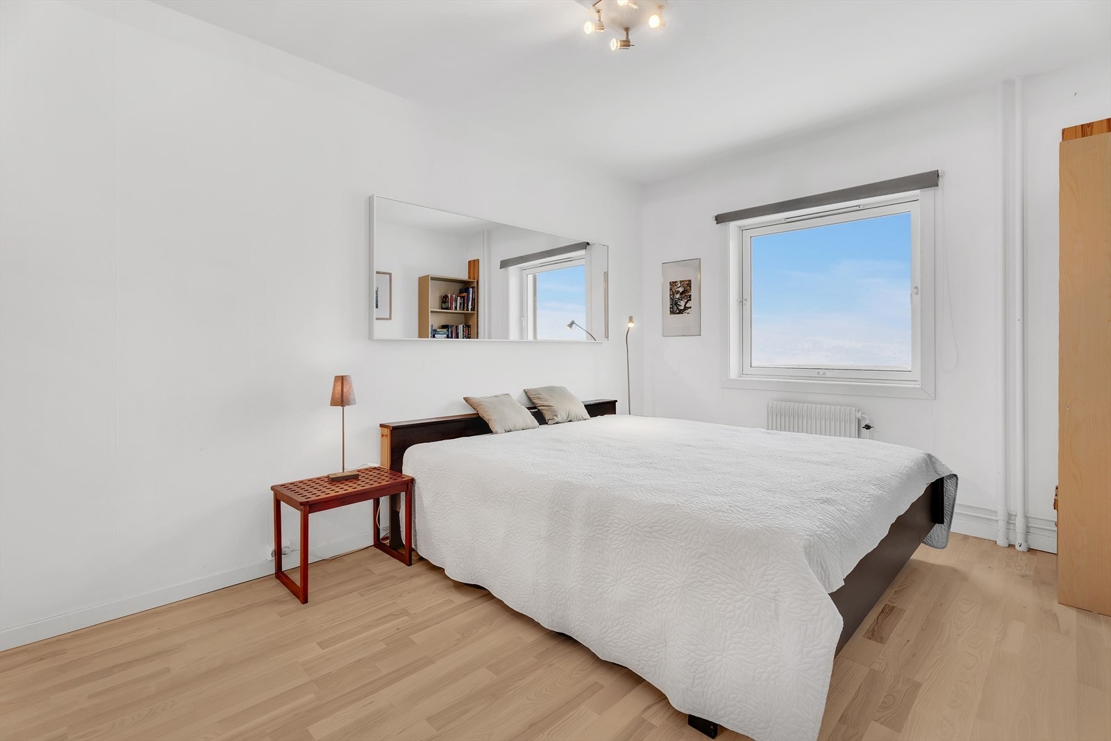 Stort soverom med parkett på gulv, malte vegger og malt tak. Det er montert en stor og praktisk skyvedørsgarderobe. Galleribilde