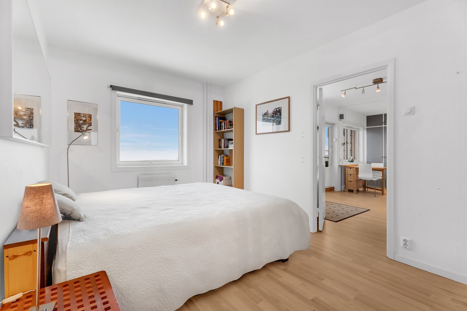 Stort soverom med parkett på gulv, malte vegger og malt tak. Det er montert en stor og praktisk skyvedørsgarderobe. Galleribilde