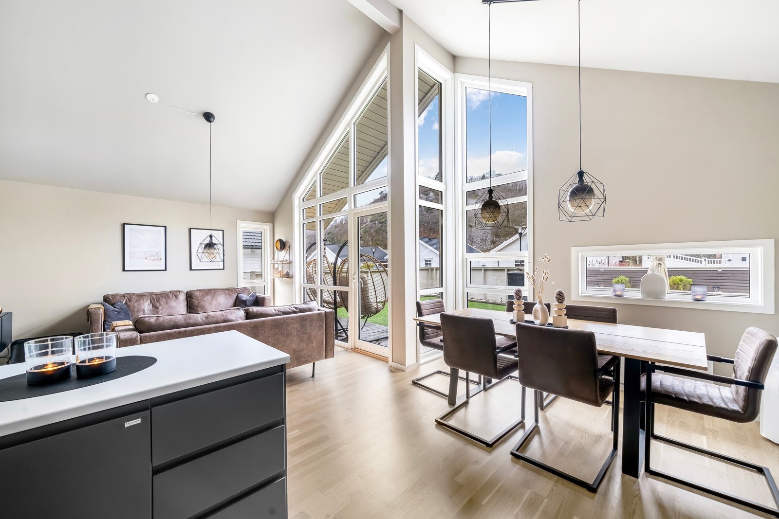 Romslig og lys stue/kjøkken løsning med store vindusflater og ekstra takhøyde Galleribilde