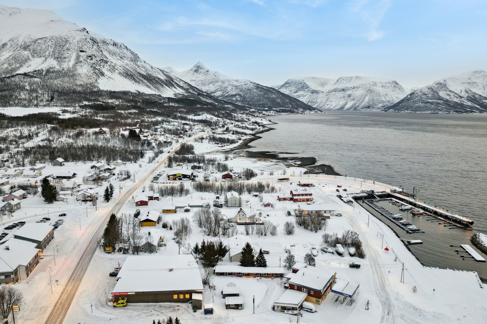 Drone bilde av eiendommen og E6 sørover og innerst i fjorden finnes tettstedet Kåfjord som fører videre til Manndalen. Galleribilde