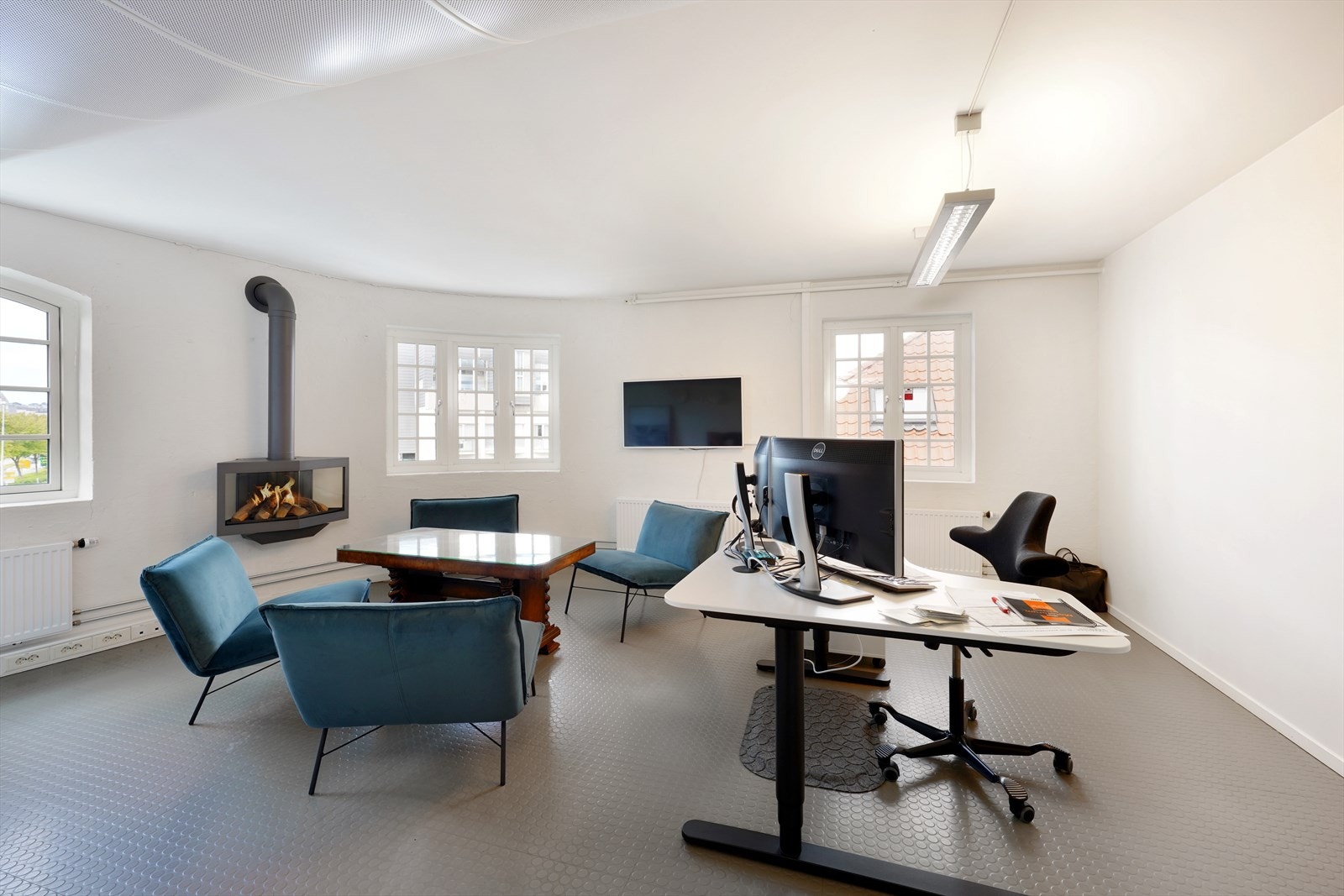 Lyst og romslig kontorlokale med store vinduer, peis og moderne arbeidsstasjoner. Perfekt for en produktiv arbeidsdag. Galleribilde