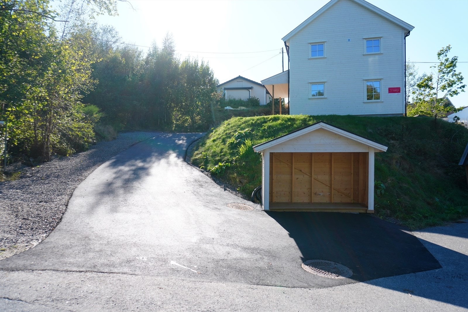 Nyasfaltert innkjørsel, postkassestativ ved veien. Galleribilde