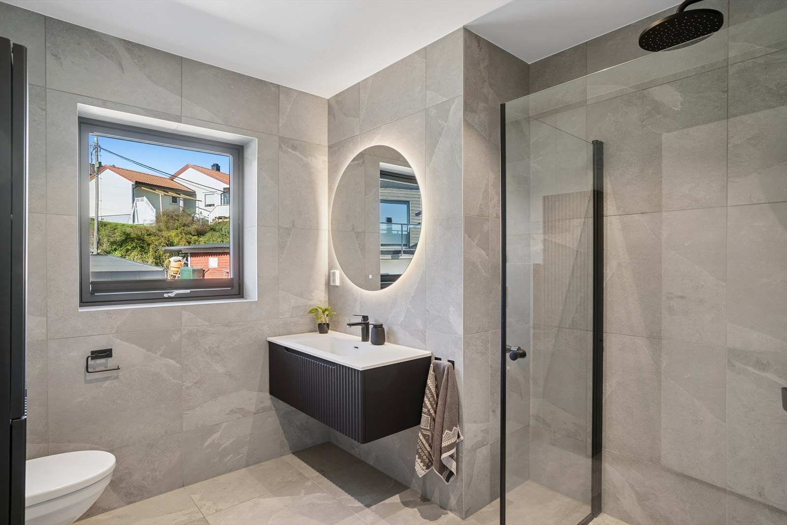 Badet er flislagt og har varmekabler. Det er dusjhjørne, vegghengt toalett og servant. Galleribilde