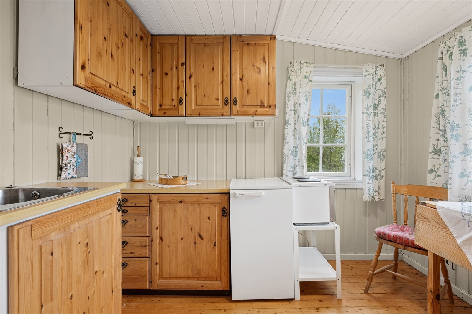 Enkelt kjøkken med profilerte eikefronter og benkeplate av typen laminat. Galleribilde