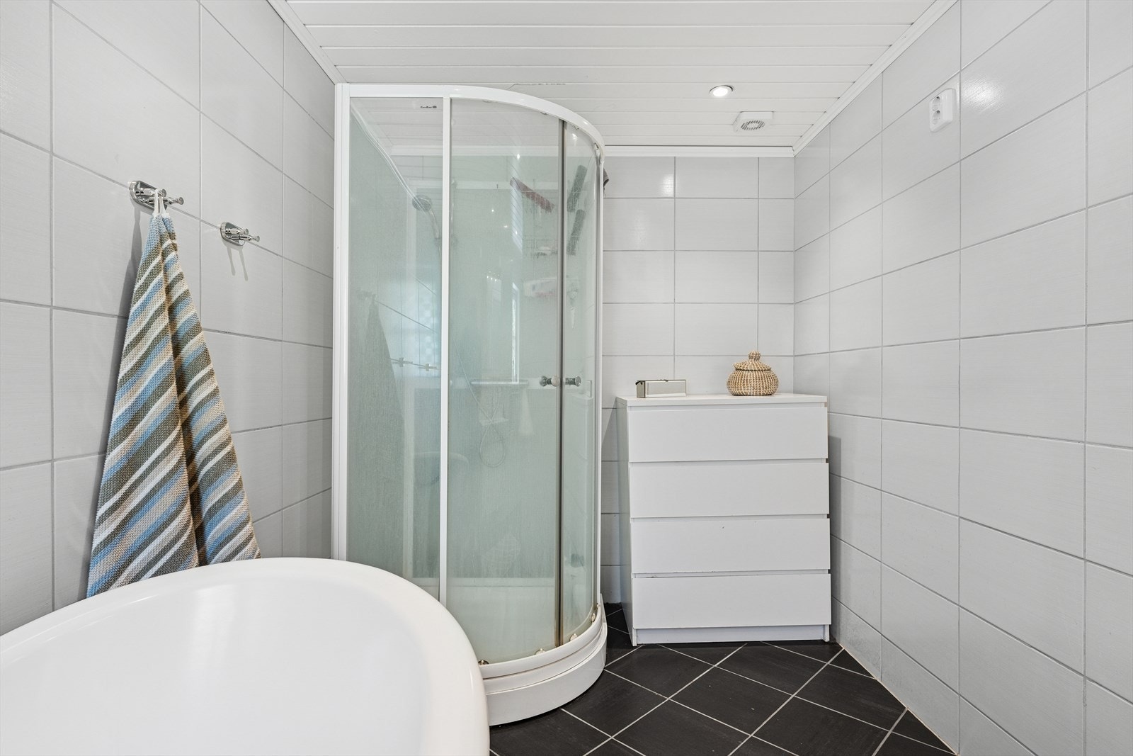 Dusjkabinett i hjørnet. Det er flislagte overflater på gulv og vegger. Galleribilde