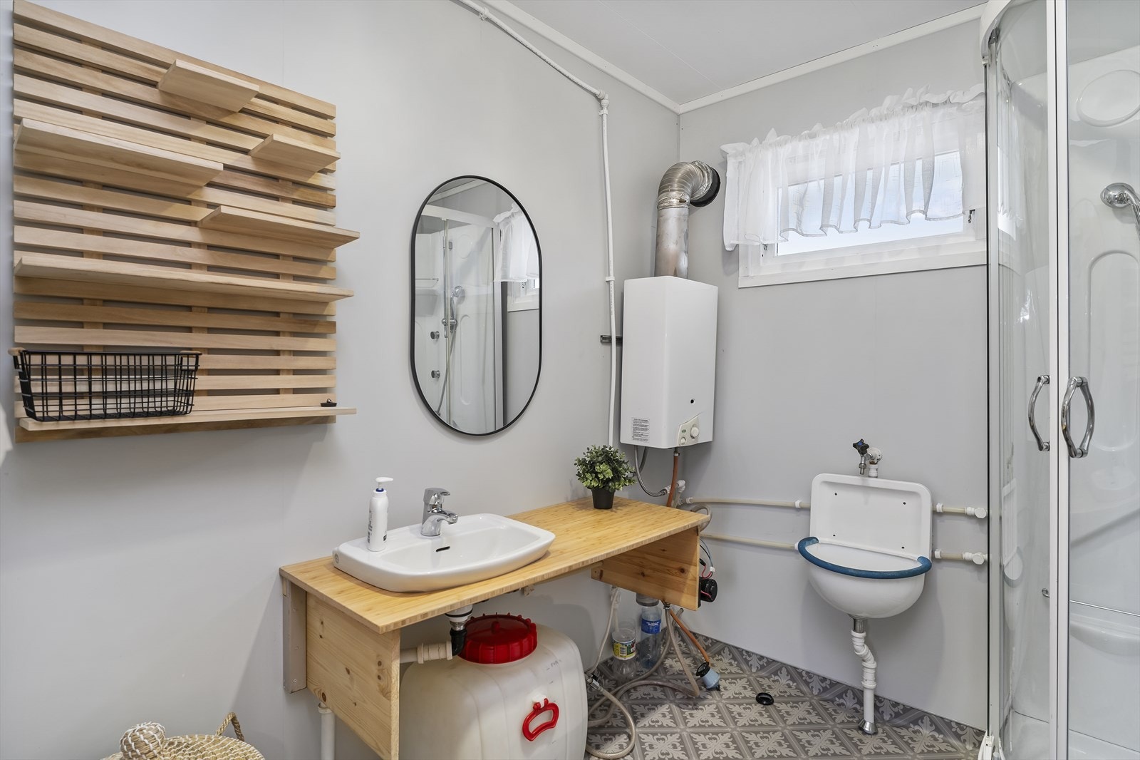 Bad med vask og dusjkabinett. Her går vannet fra utvendig regnvannstank, samt dunk fra medbrakt vann. Galleribilde