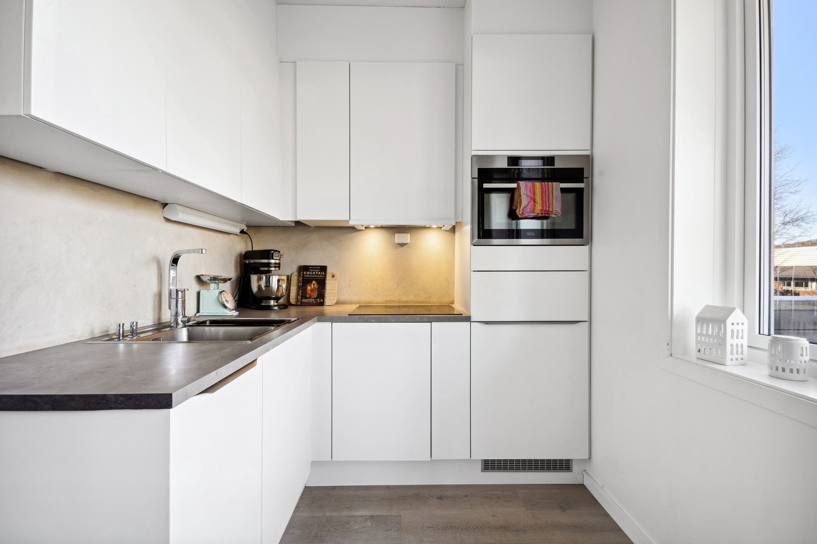 Moderne kjøkken med lyse fronter og en mørkere benkeplate som står godt til stilen. Galleribilde