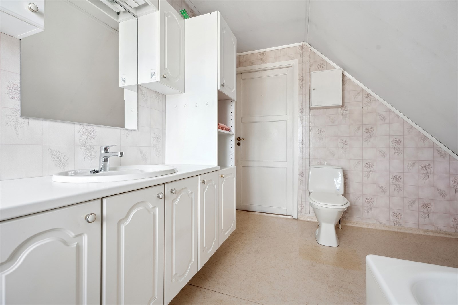 Badet er innredet med en servant med underskap, badekar med dusj og gulvmontert wc. Galleribilde