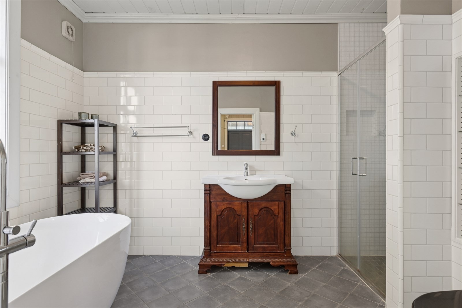 Et klassisk bad med høyglansede fliser, mosaikk i dusjsonen og frittstående badekar foran vinduet. Her kan du senke skuldrene. Galleribilde