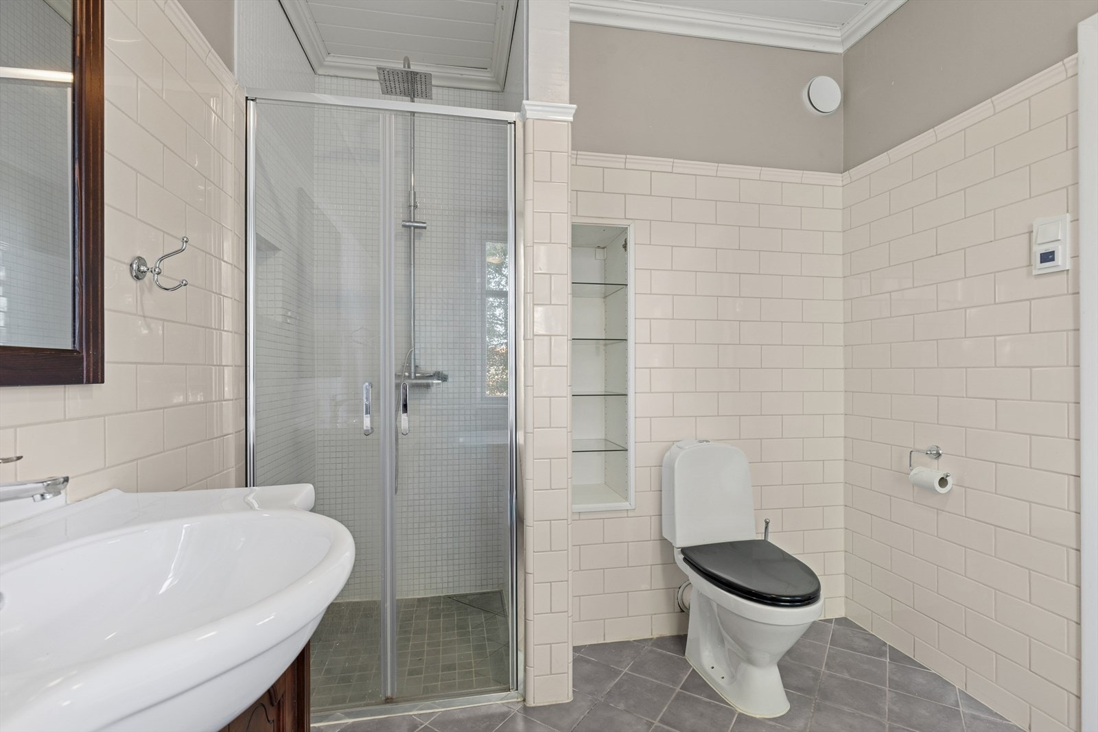 Gjennomført bad med god takhøyde og vakker høyglanset flis som understreker den gode takhøyden i rommet. Galleribilde