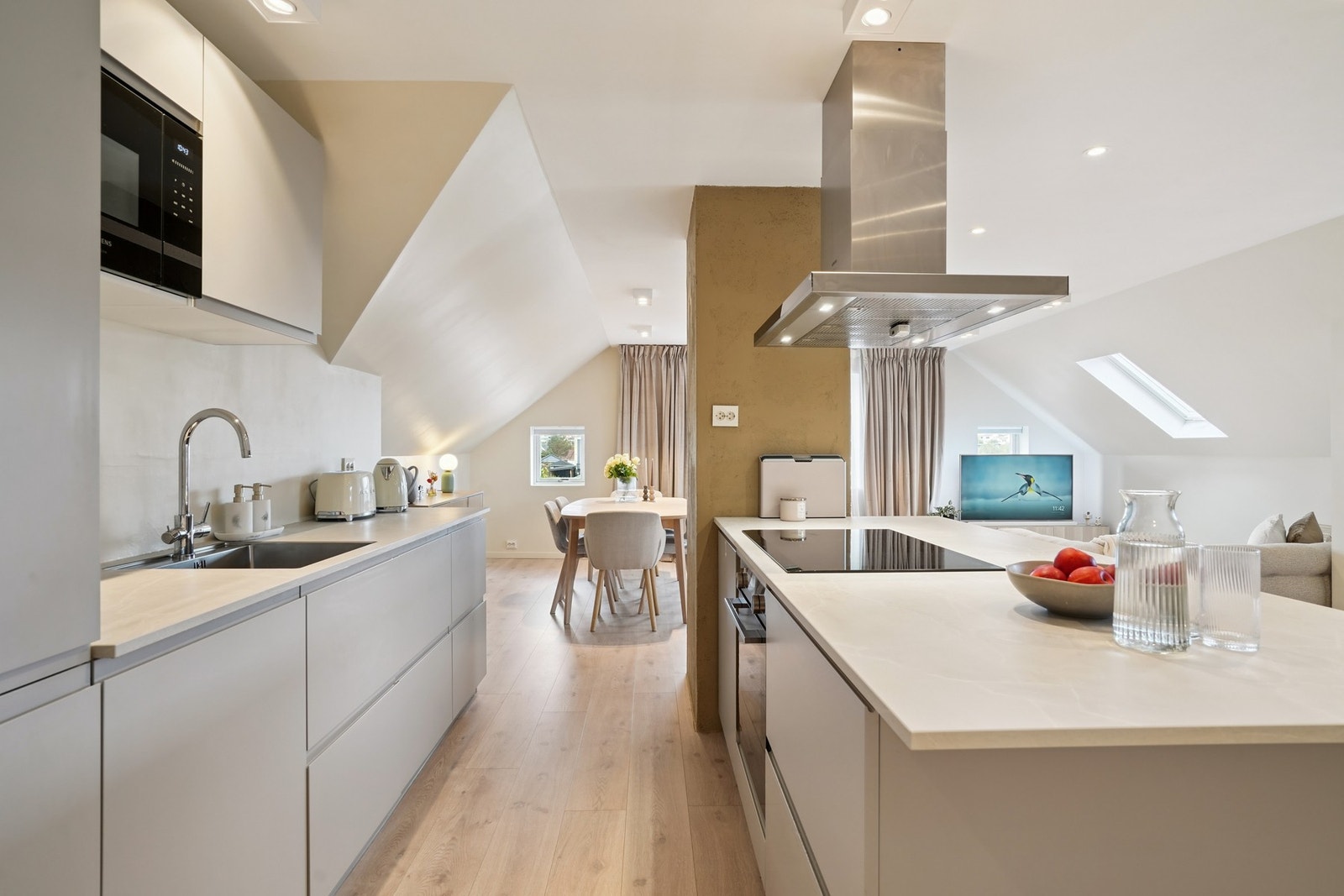 Praktisk åpen-stue kjøkken løsning med et moderne kjøkken og en romslig stue. Galleribilde