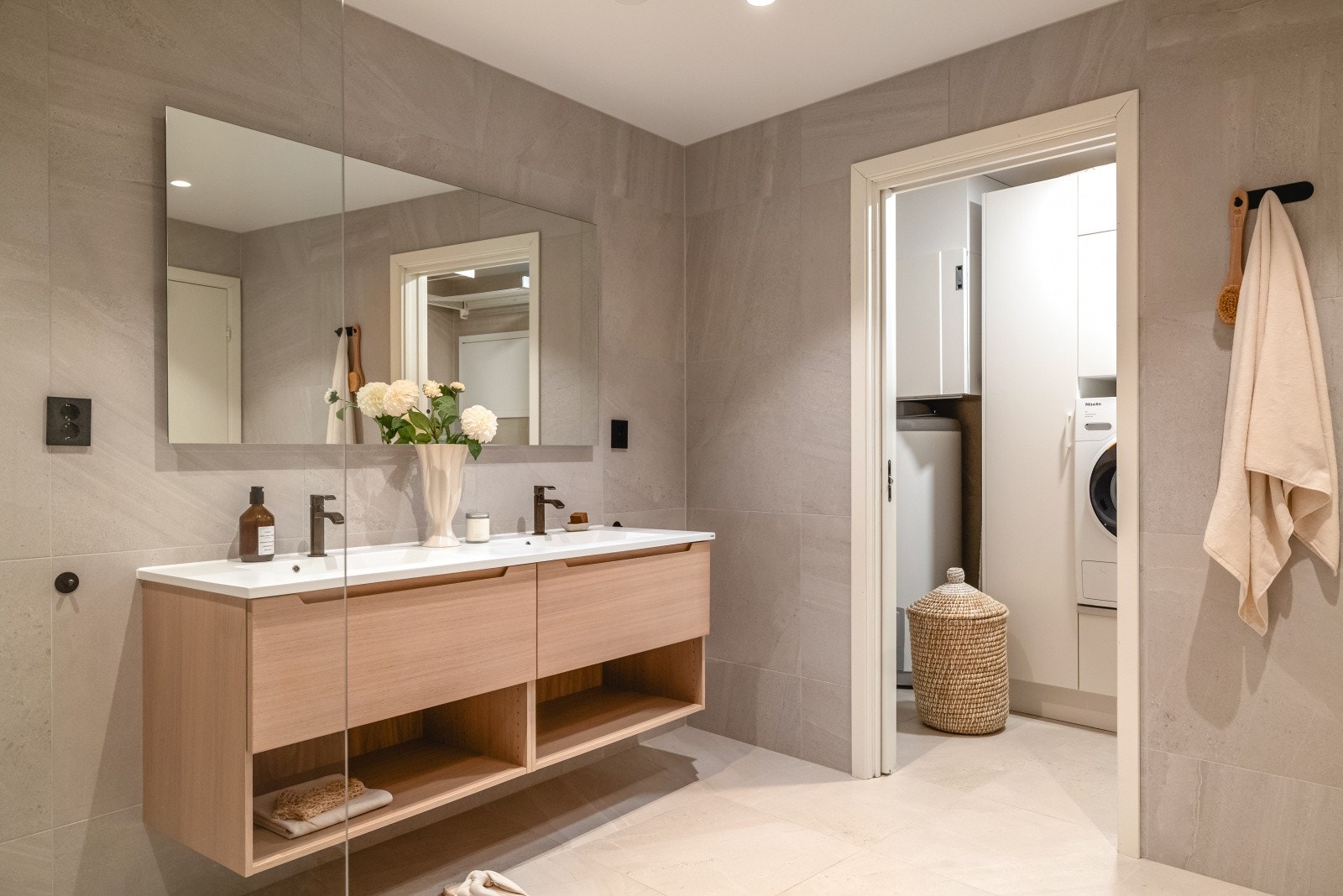 Store og tidsriktige fliser på gulv og vegger og innredning bestående av dusjnisje, veggtoalett og baderomsinnredning med heldekkende servant, samt belyst speil. Galleribilde