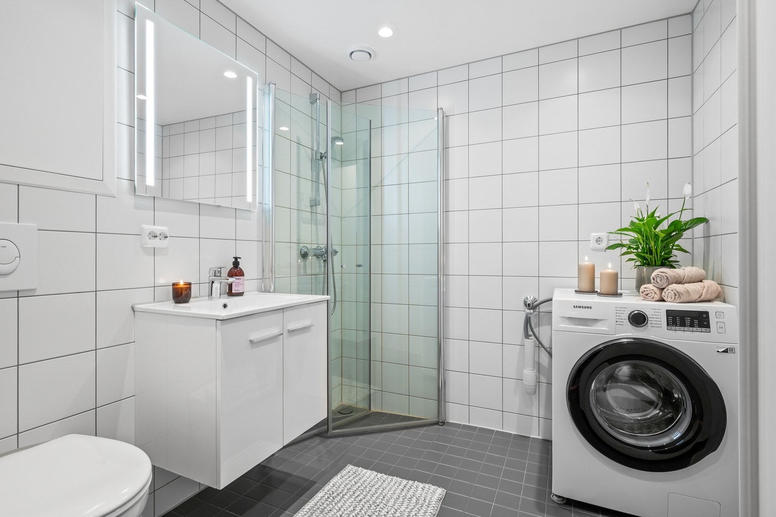 Badet er utstyrt med dusjhjørne, mekanisk avtrekk, opplegg for vaskemaskin, servant, servantskap, rørfordelingsskap og wc. Galleribilde