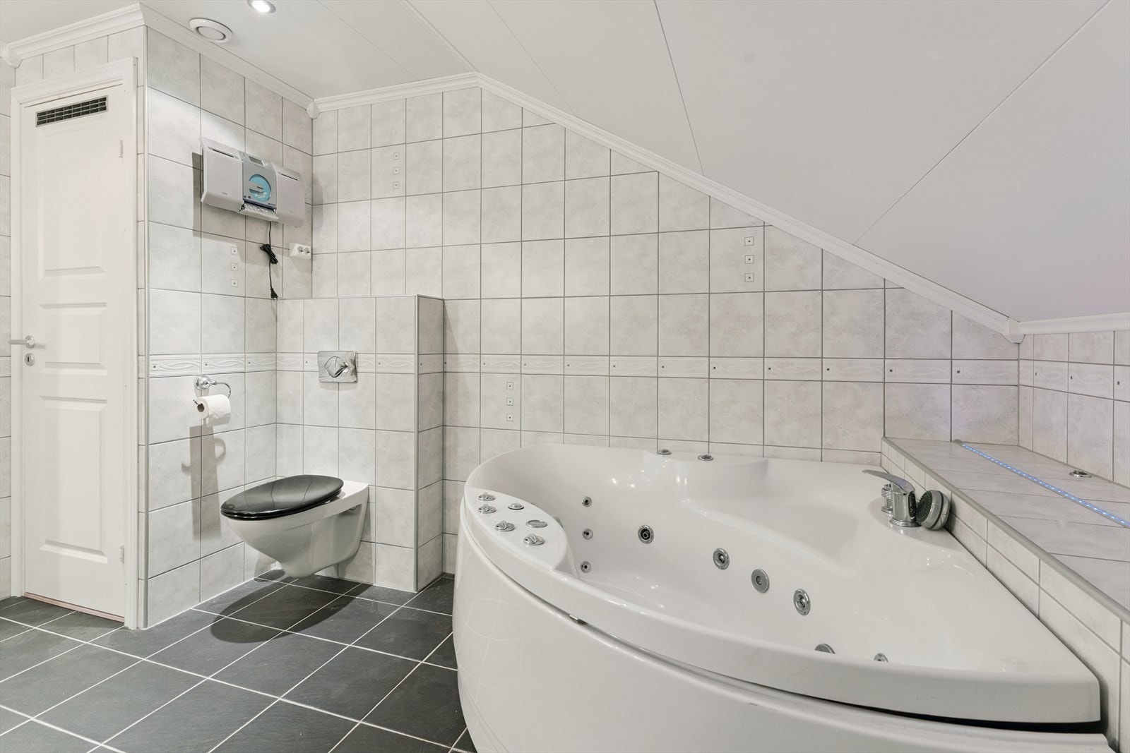 Baderom i loftetasje med vegghengt toalett og plass for hjørnebadekar Galleribilde