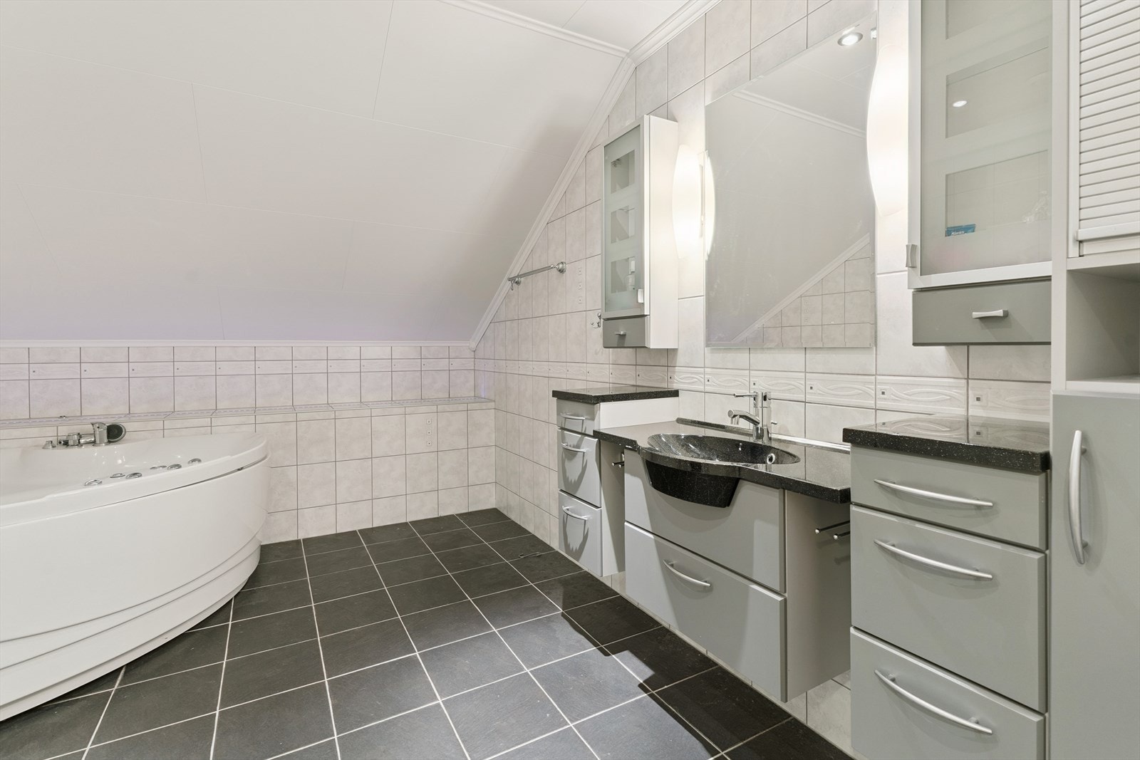 Skuffeinreiing med helstøypt servant og skap for oppbevaring. Her er det elektriske varmekablar på flislagt golv. Det er også flis på vegg. Galleribilde