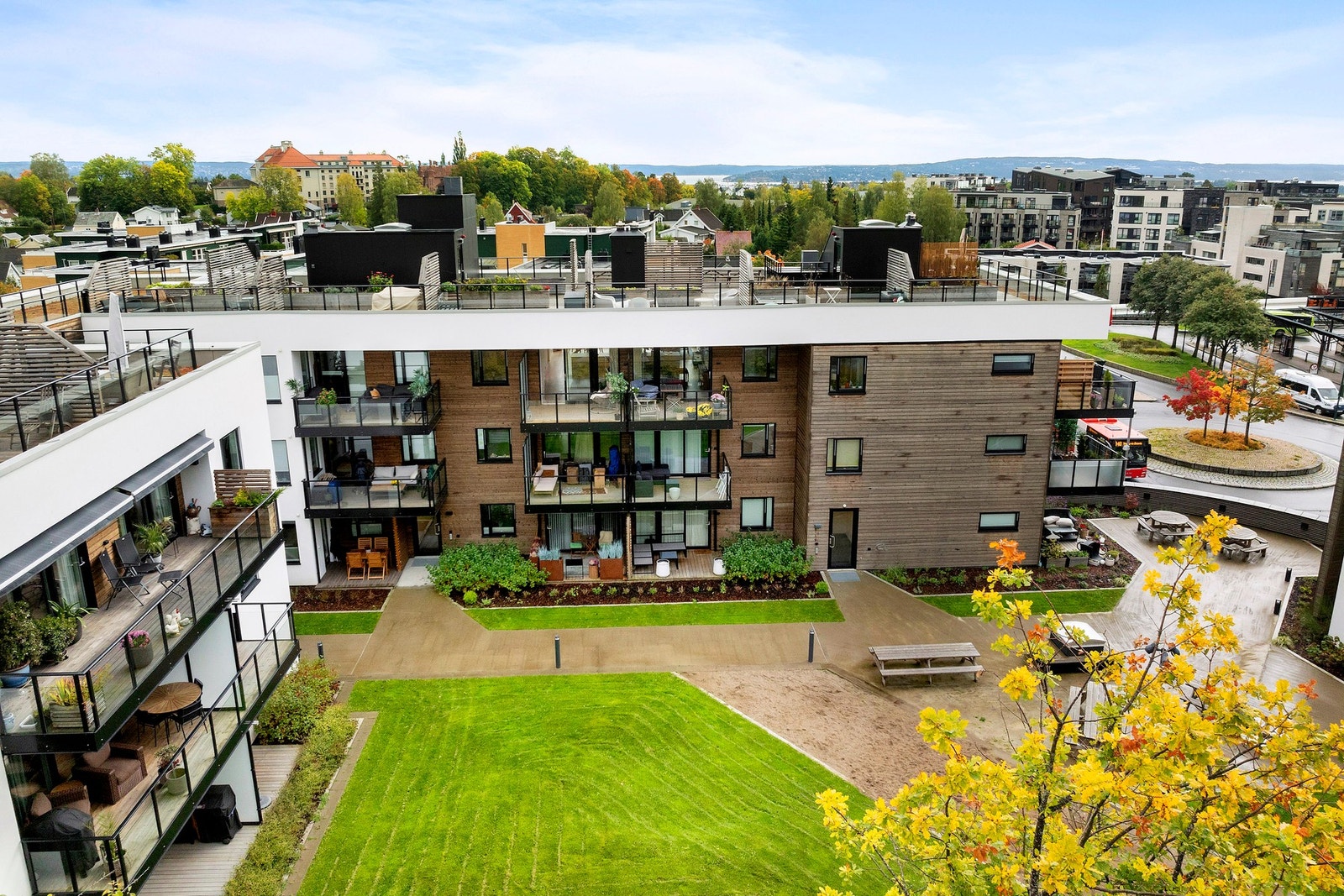 Pent opparbeidet fellesareal med flere sittegrupper, lekeplass og gressplen. Galleribilde