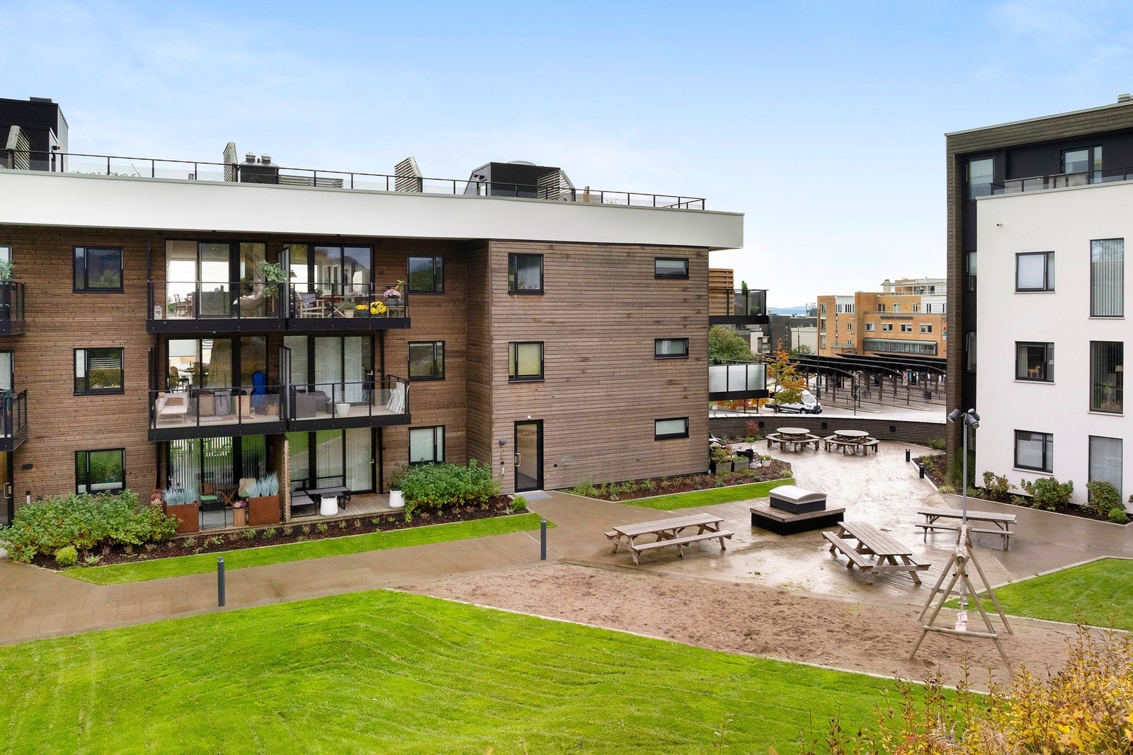 Pent opparbeidet fellesareal med flere sittegrupper, lekeplass og gressplen. Galleribilde