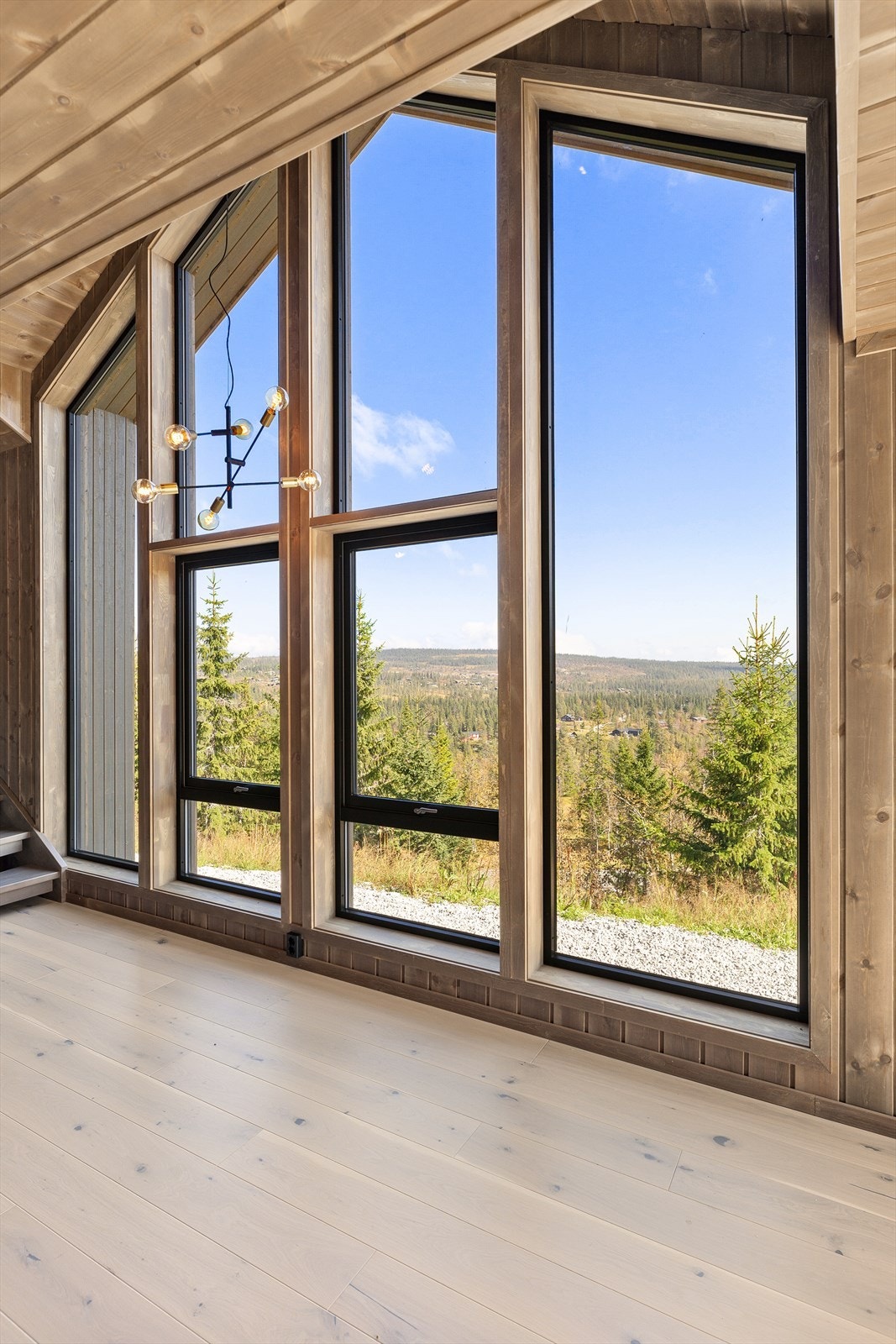 Stuen har en fantastisk takhøyde og preges av arkitektoniske vindusflater som strekker seg fra gulv til tak. Galleribilde