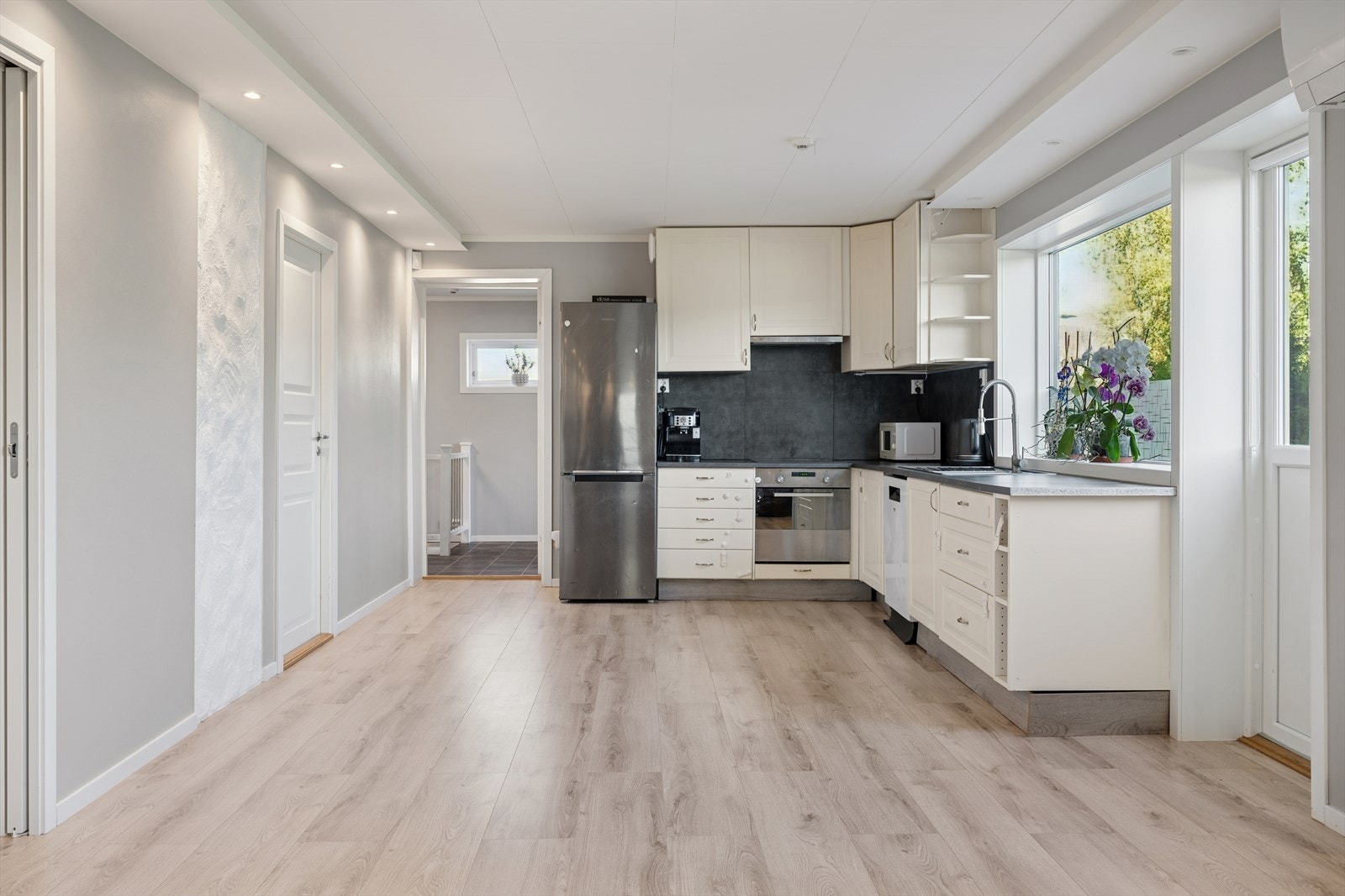 Kjøkkenet er lyst og tidløst. Innredning med slette fronter og benkeplate av typen laminat. Galleribilde