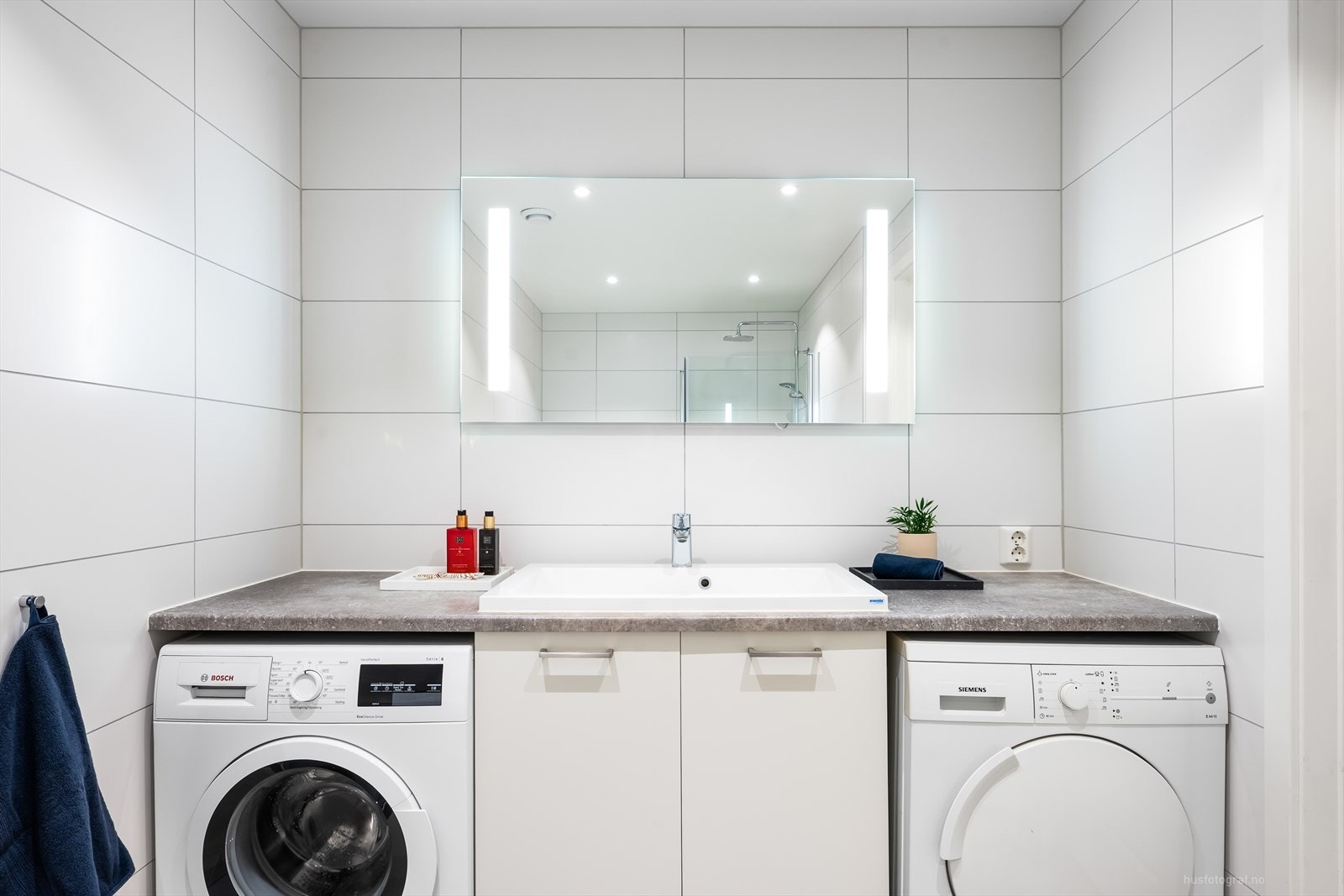 Baderomsinnredning i lys utførelse med nedfelt servant, rom for oppbevaring i skuffer og speil med belysning. Videre er badet utstyrt med vegghengt toalett, dusjhjørne med regnfalldusj og badekar. Rommet har opplegg for vaskemaskin og tørketrommel. Galleribilde