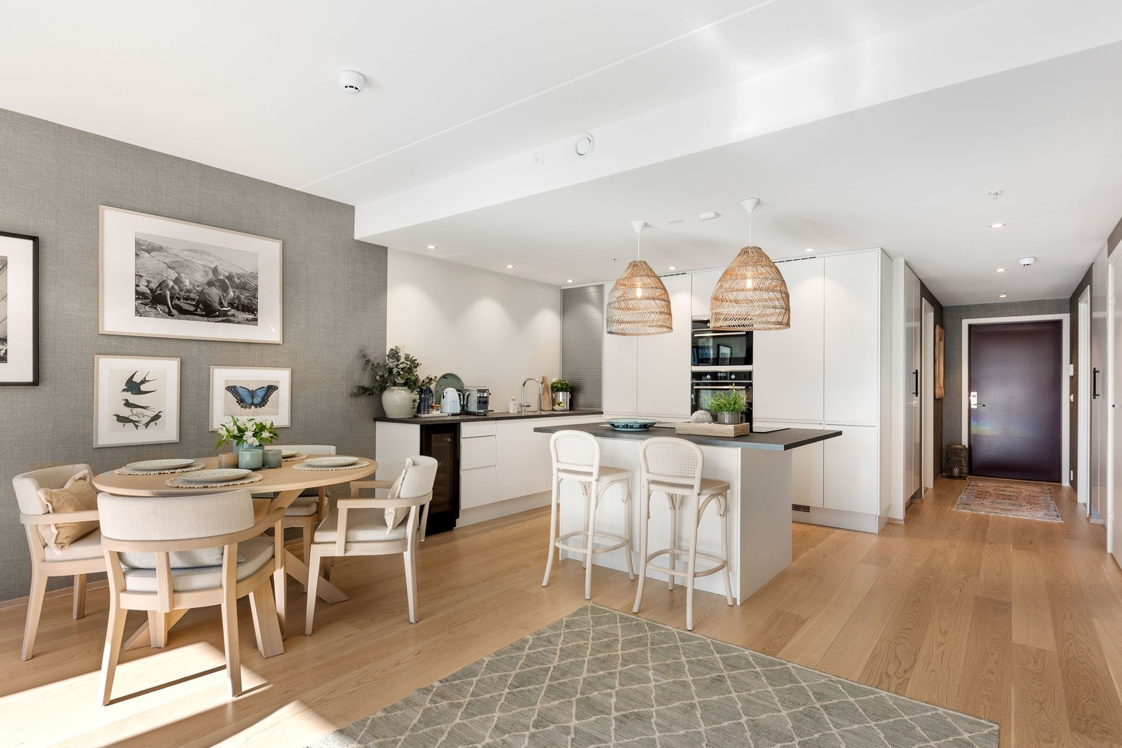 Åpen kjøkkenløsning med spiseplass og øy. Lyse flater og moderne belysning. Galleribilde