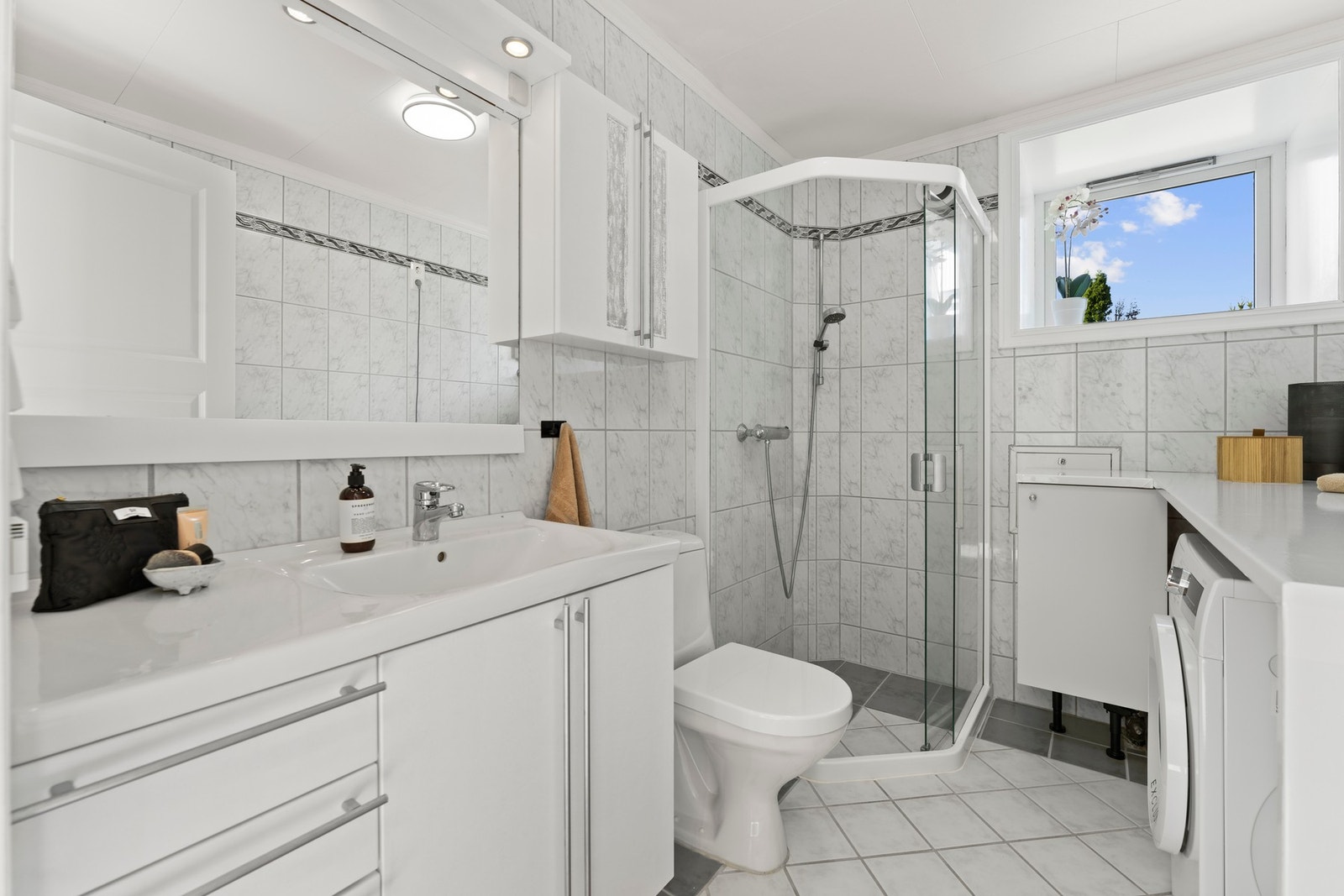 Flislagt bad med gulvvarme, dusjhjørne, servant og opplegg for vaskemaskin. Galleribilde