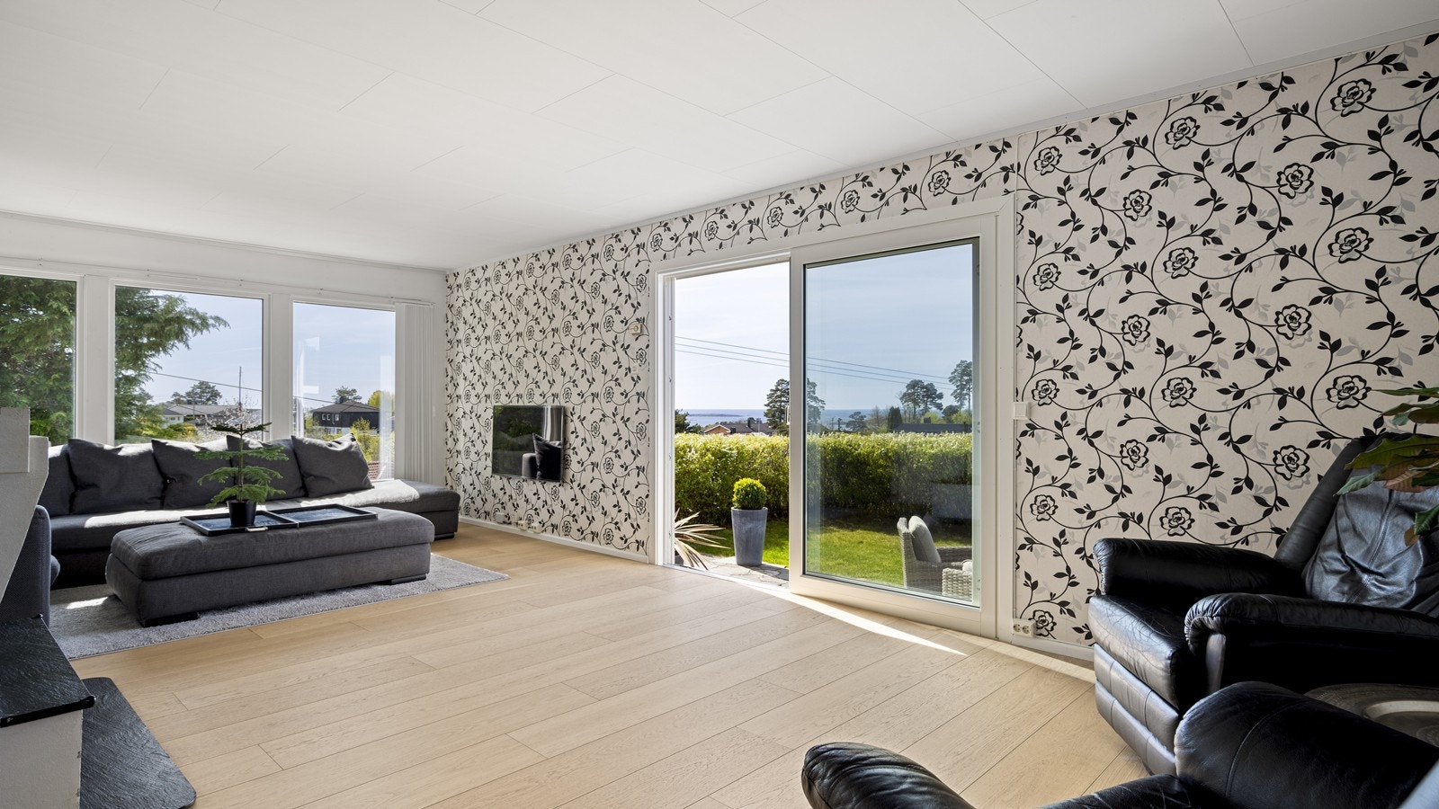 Lys og luftig stue med store vinduer og direkte utgang til hagen og sjøutsikt Galleribilde