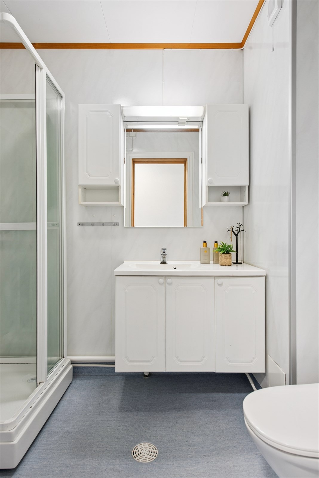 Rommet har våtromsbelegg på gulv, servant med underskap og speilskap for oppbevaring. Galleribilde