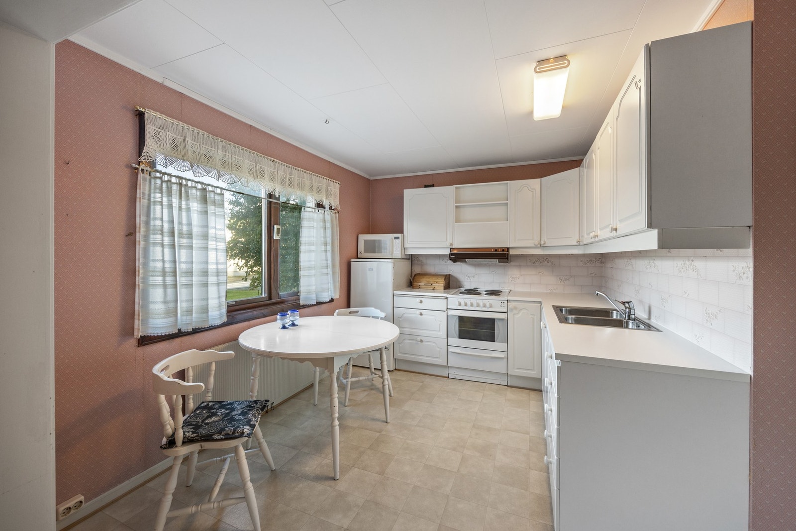 Pen kjøkkeninnredning med avsatt plass for komfyr og kjøleskap Galleribilde