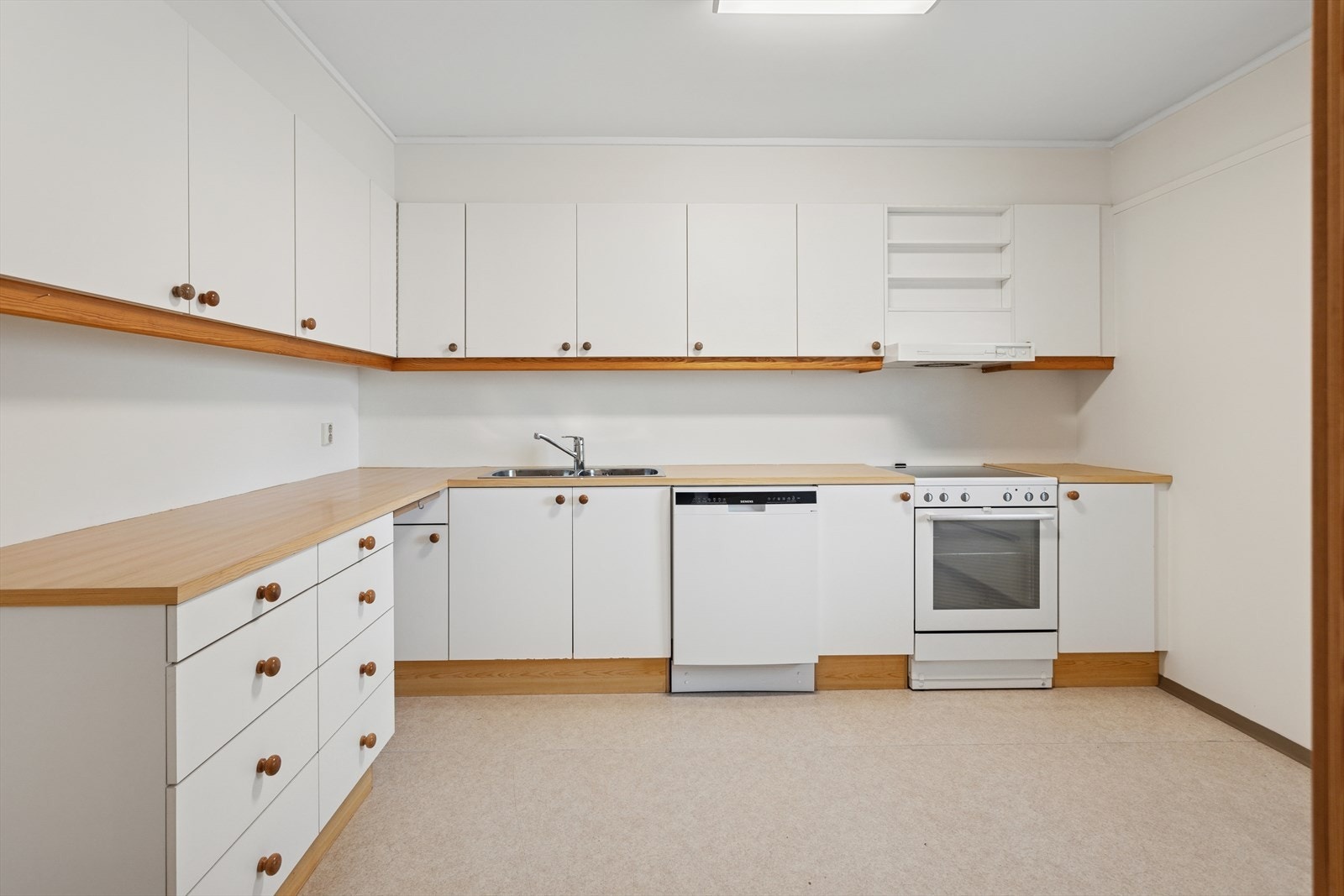 Kjøkkeninnredningen består av hvite glatte fronter, laminat benkeplate, nedfelt dobbel oppvaskkum, belysning under skap og ventilator. Galleribilde