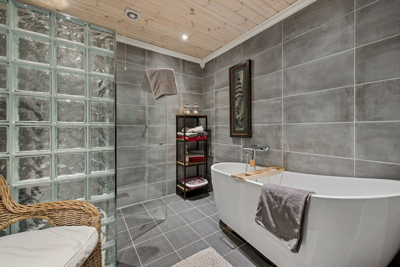 Fliser med varmekabler på gulv, flislagte vegger og panel med downlights i himlingen gir en lun og moderne atmosfære. Galleribilde